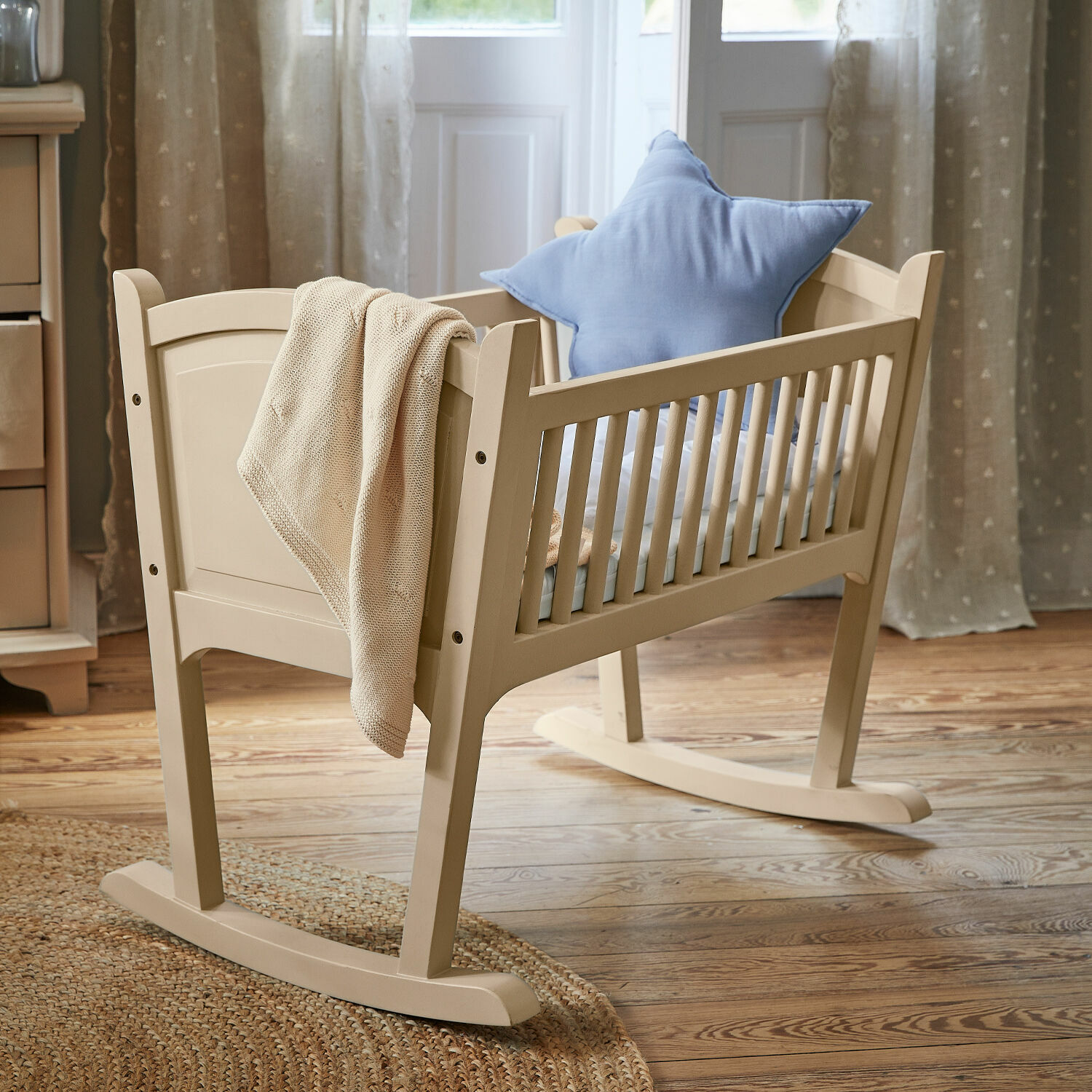 Wiege Aiguillon Beige lackierte Holz-Kinderwiege mit blauem Sternkissen und gestrickter Decke im Zimmer