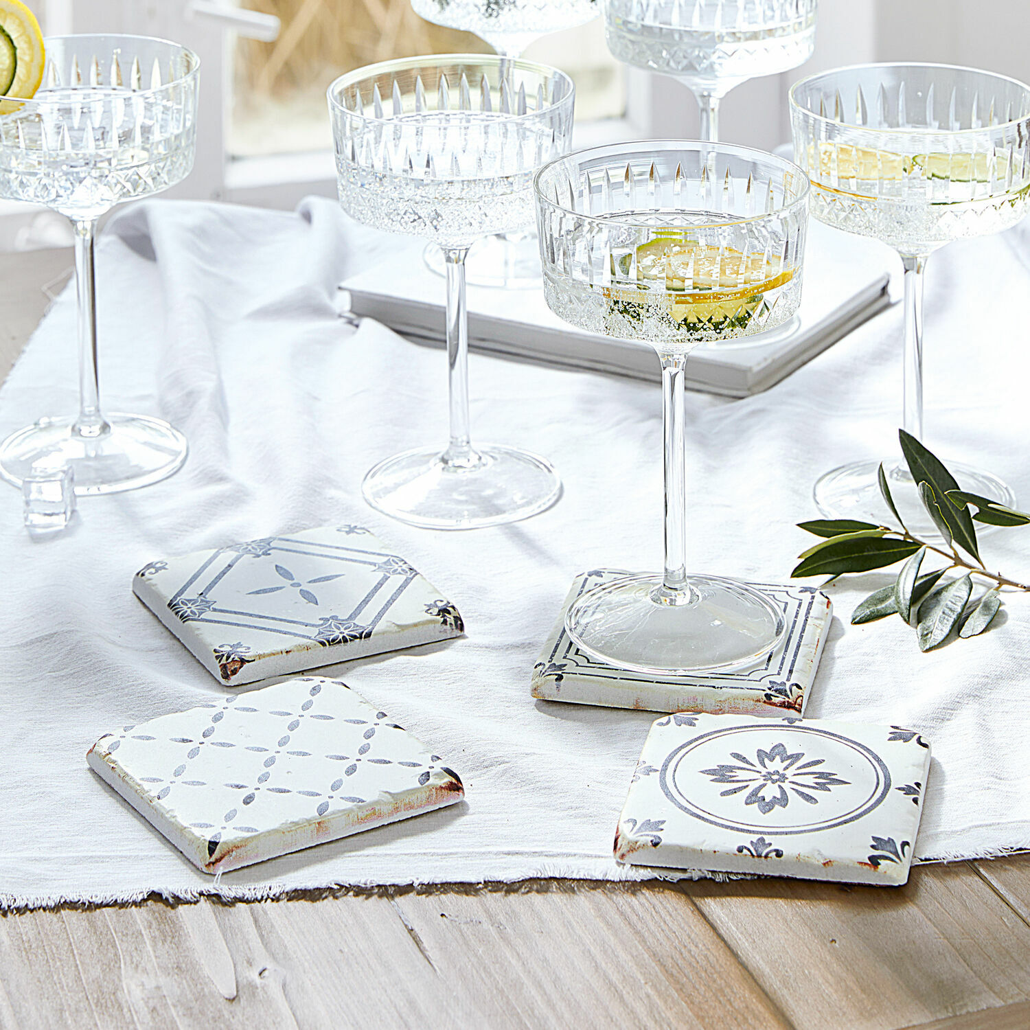 Untersetzer 4er Set Emma Set aus weissen und grauen Keramikuntersetzern mit Muster auf hellem Holztisch mit Gläsern