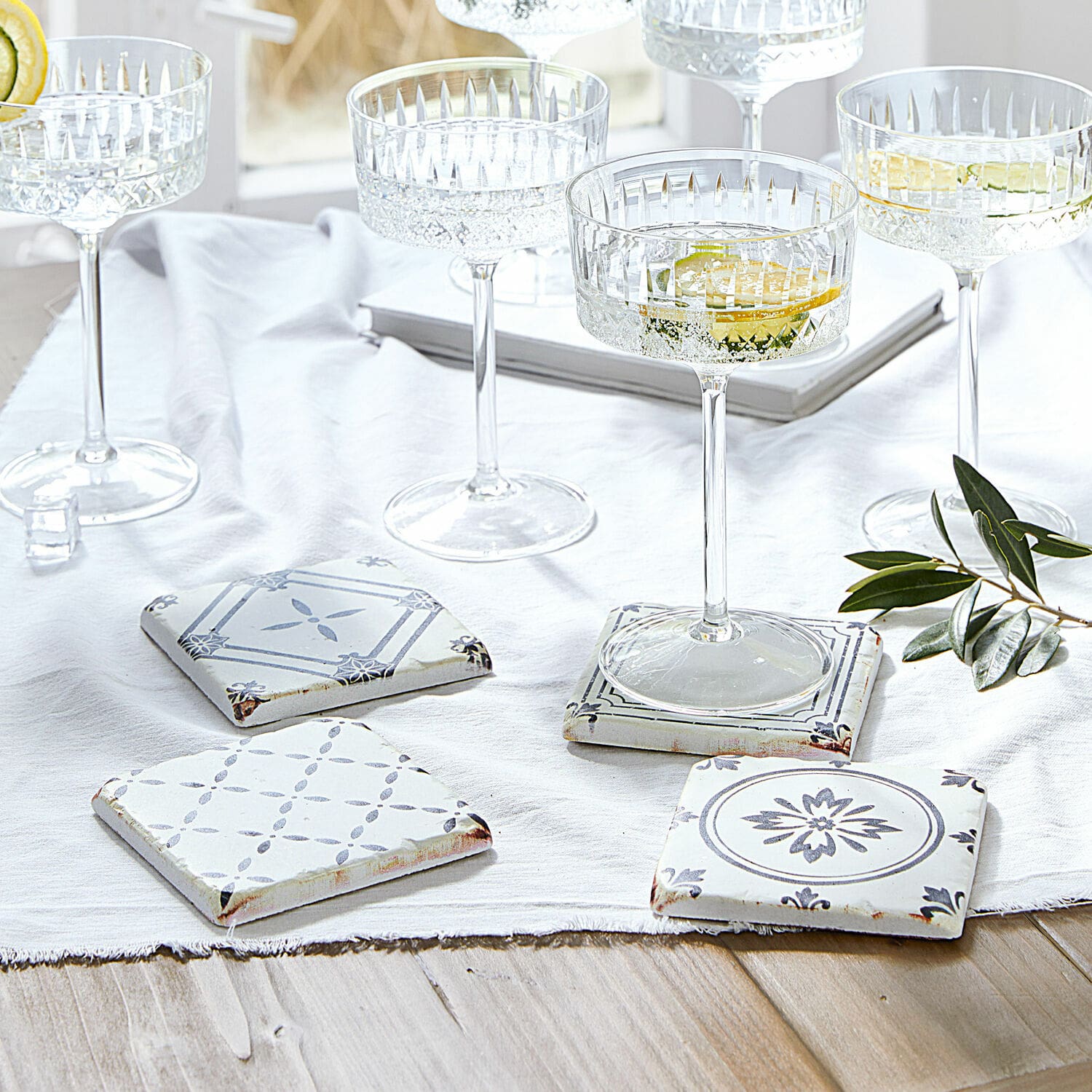 Untersetzer 4er Set Emma Set aus weissen und grauen Keramikuntersetzern mit Muster auf hellem Holztisch mit Gläsern