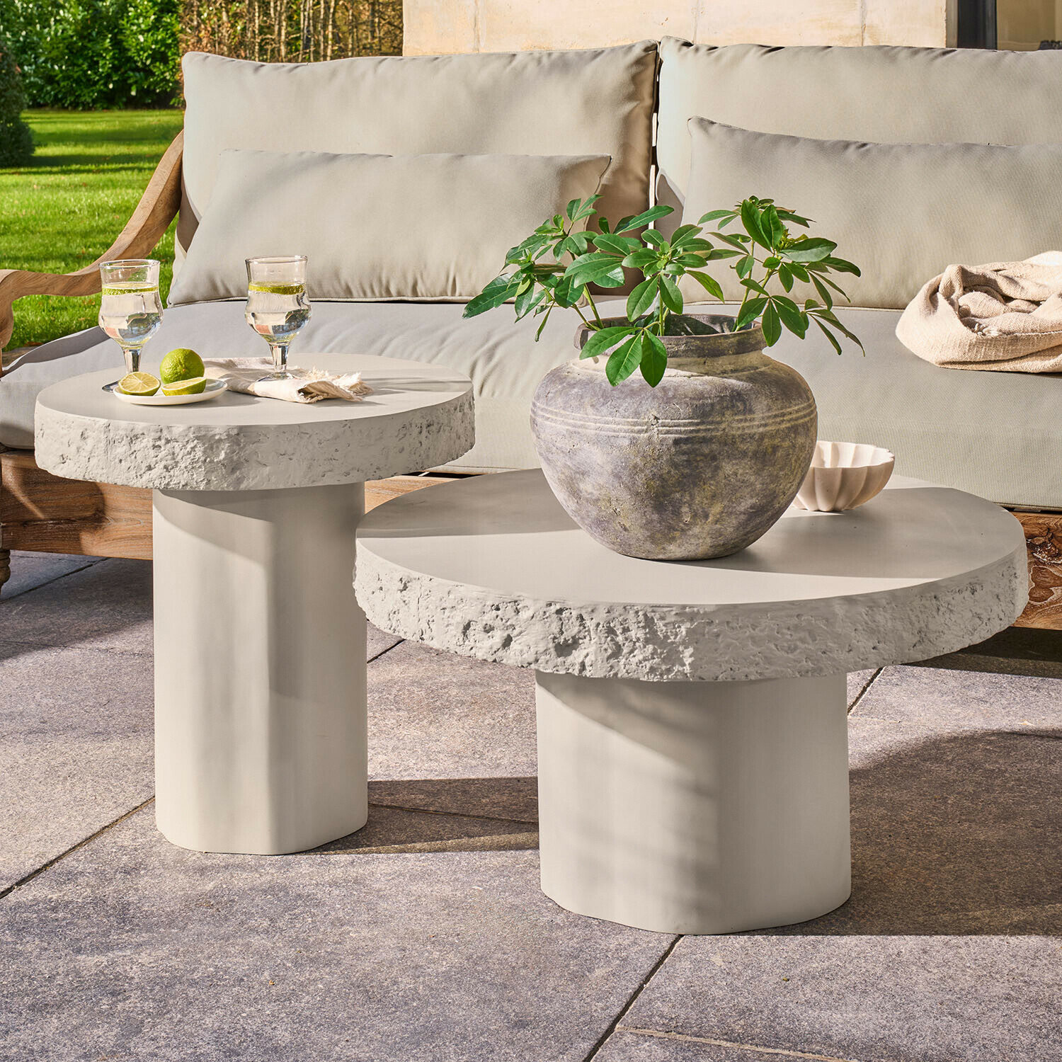 Couchtisch 2er Set Tivoliq Set mit zwei runden Beistelltischen aus hellgrauem Beton auf Terrasse mit Pflanze und Getränken