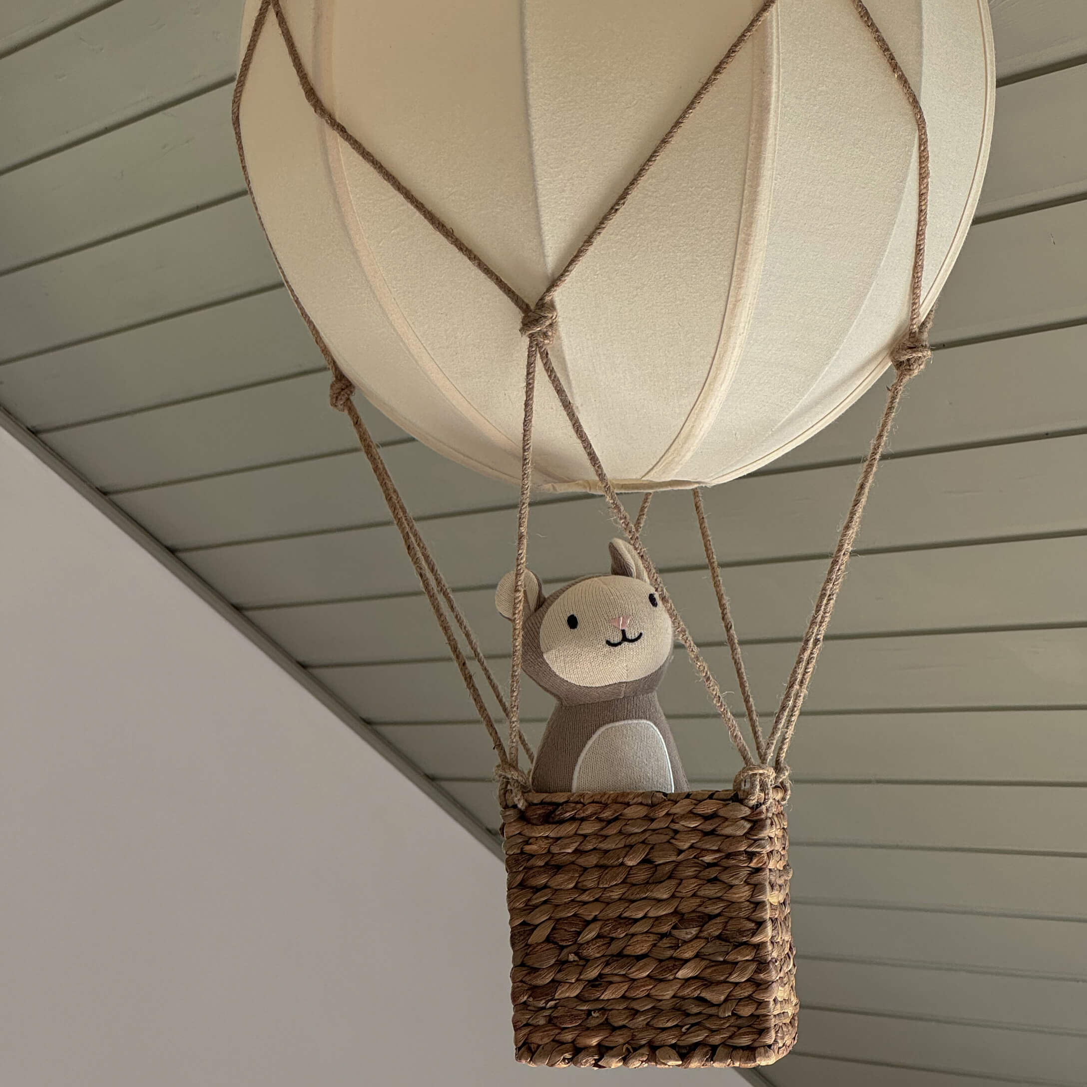 Dekorativer hängender Ballon mit Weidenkorb und beigefarbenem Plüschtier in modernem Raum