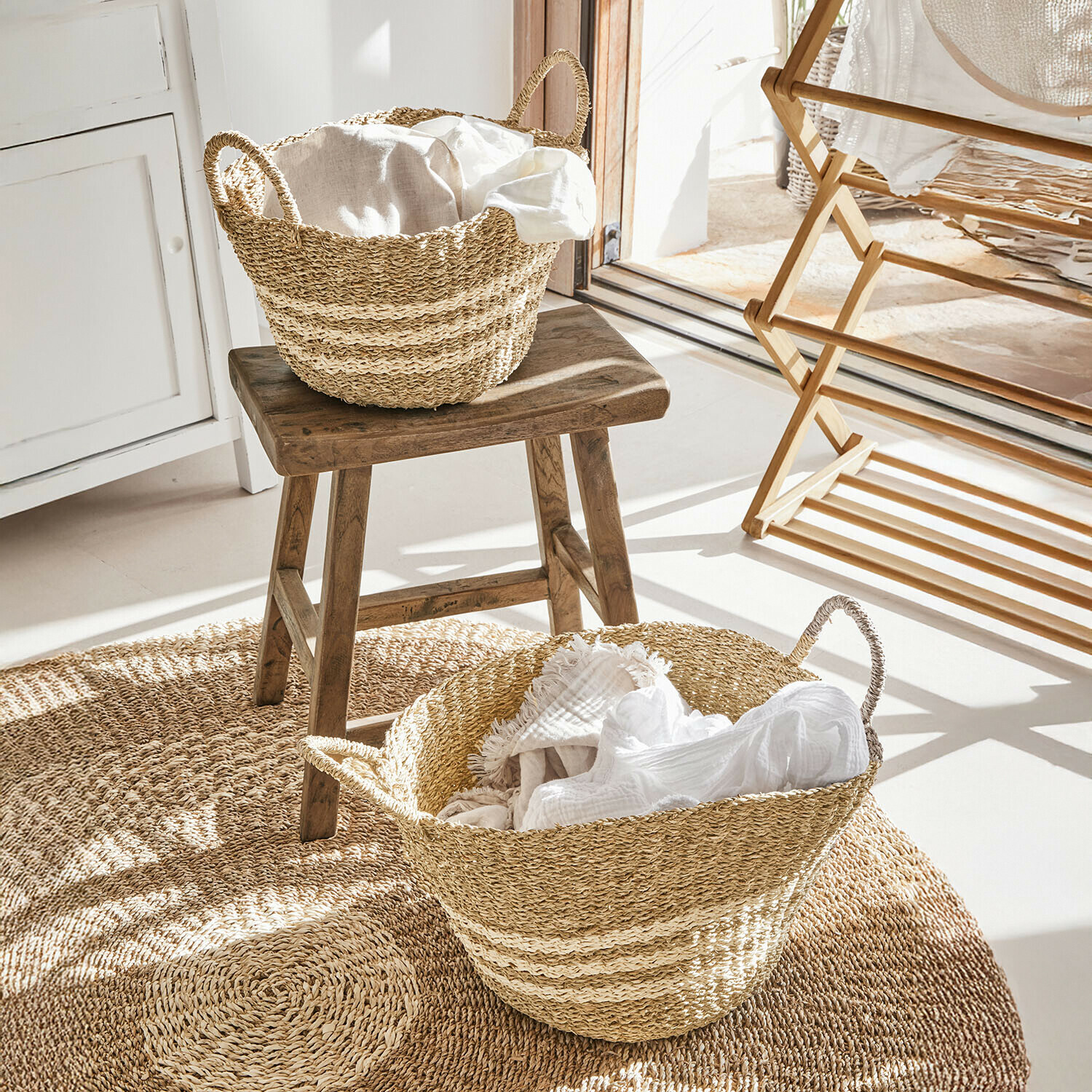Korb 2er Set Farivon Naturfarbene Seegras-Körbe mit weißen Stoffen auf rundem Teppich in hellem Raum