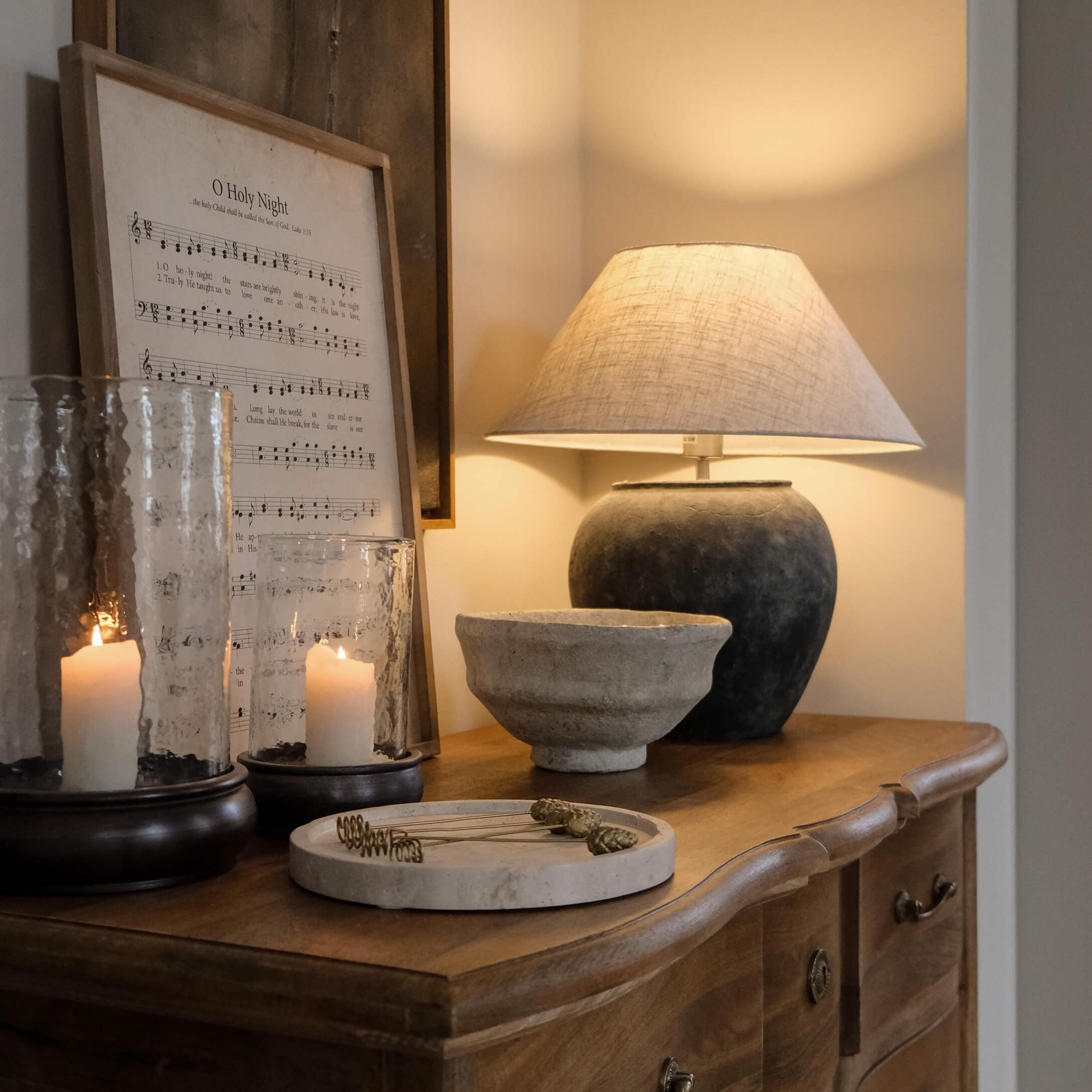 Tischlampe mit schwarzem Keramikfuß und beigem Lampenschirm auf Holzkommode mit Dekorationen