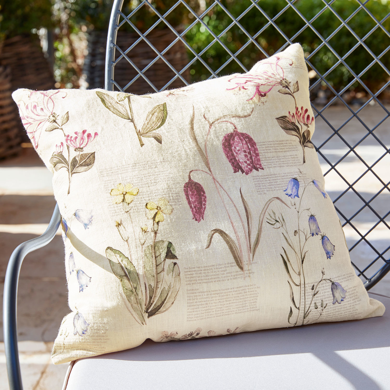 Kissenhülle Fournier Beige Leinenkissen mit Vintage-Blumenmuster auf Gartenstuhl im Sonnenlicht