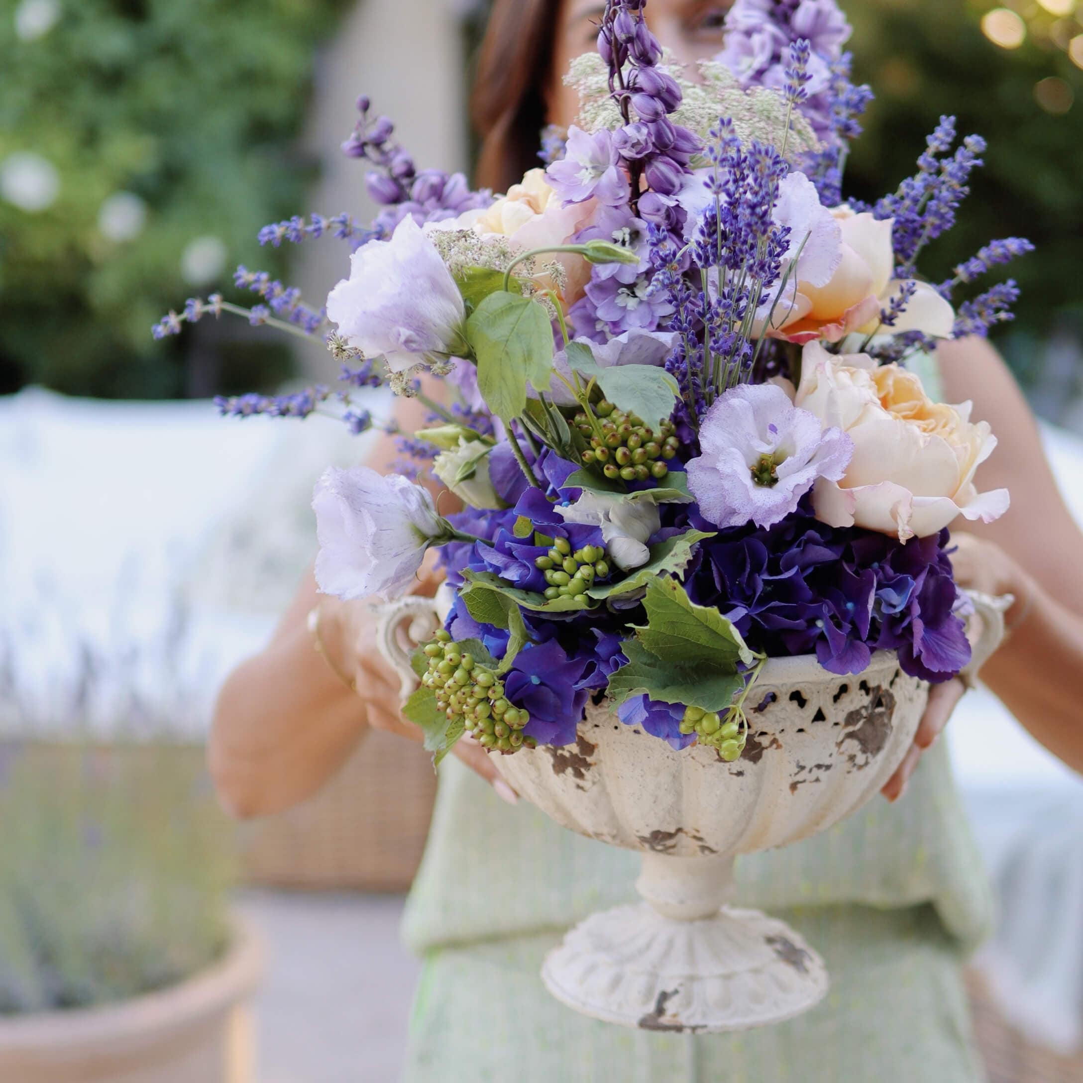 Strauß mit violetten und cremefarbenen Blumen in dekorativer weisser Keramikvase auf Fuss