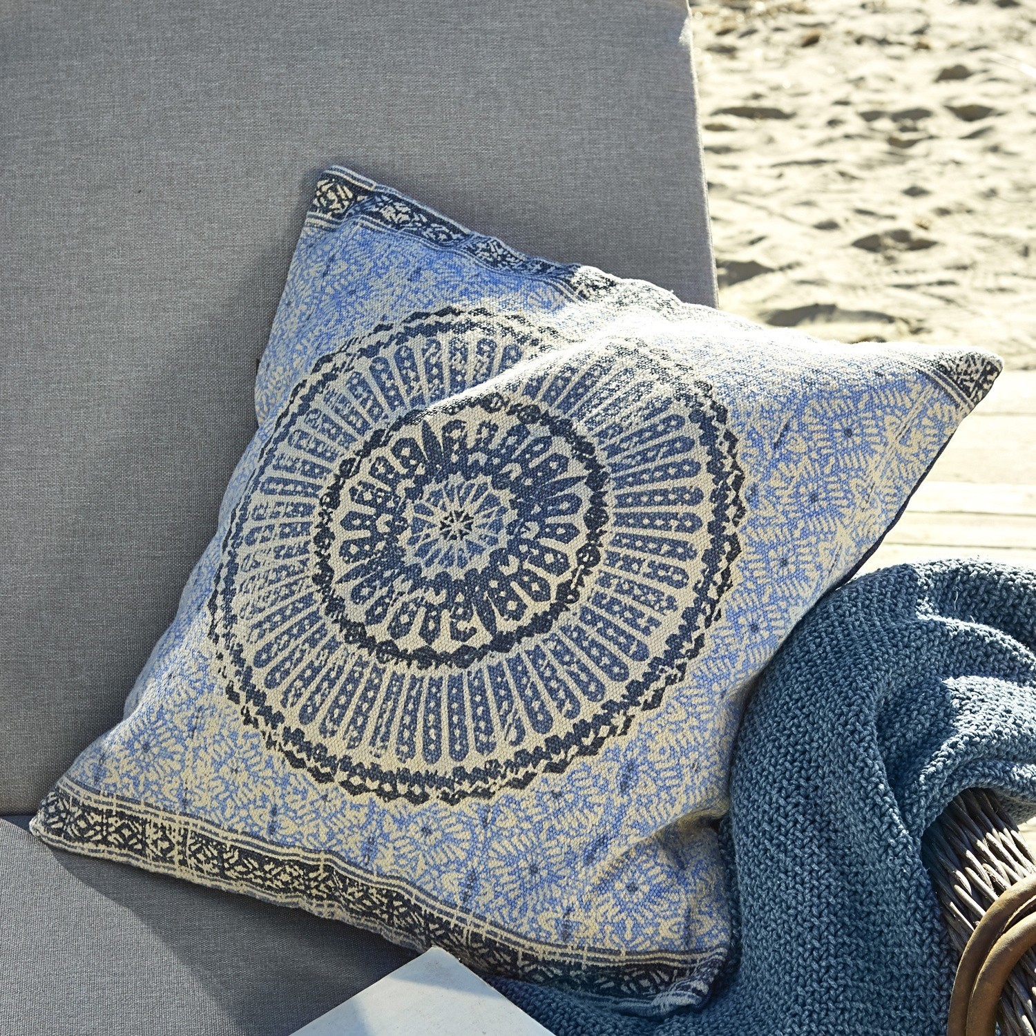 Dekoratives Baumwollkissen in Blau-Beige mit orientalischem Muster auf grauem Sofa