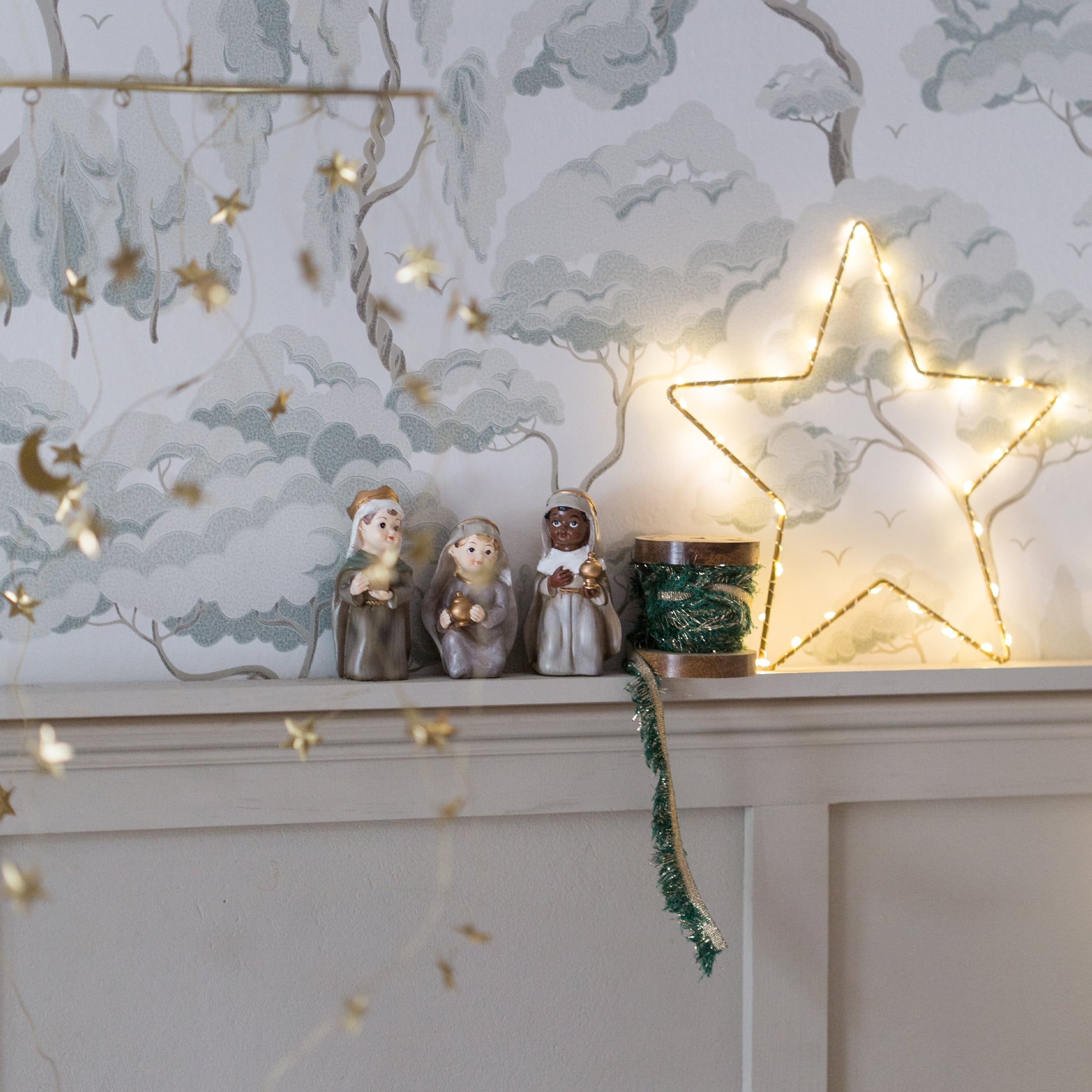 Weihnachtsdekoration mit drei Heiligen Drei Könige Figuren und beleuchteter Stern auf weissem Regal