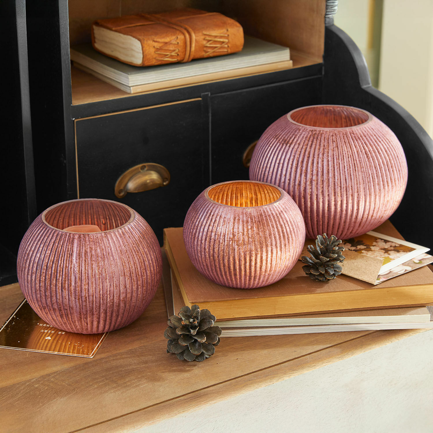 Windlicht 3er Set Jalimeen Drei rosa gerippte Glas-Teelichthalter auf Holztisch mit Naturdekorationen arrangiert