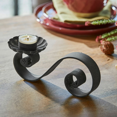 Schwarzer Metallkerzenhalter mit geschwungenem Design für Teelicht auf Holztisch