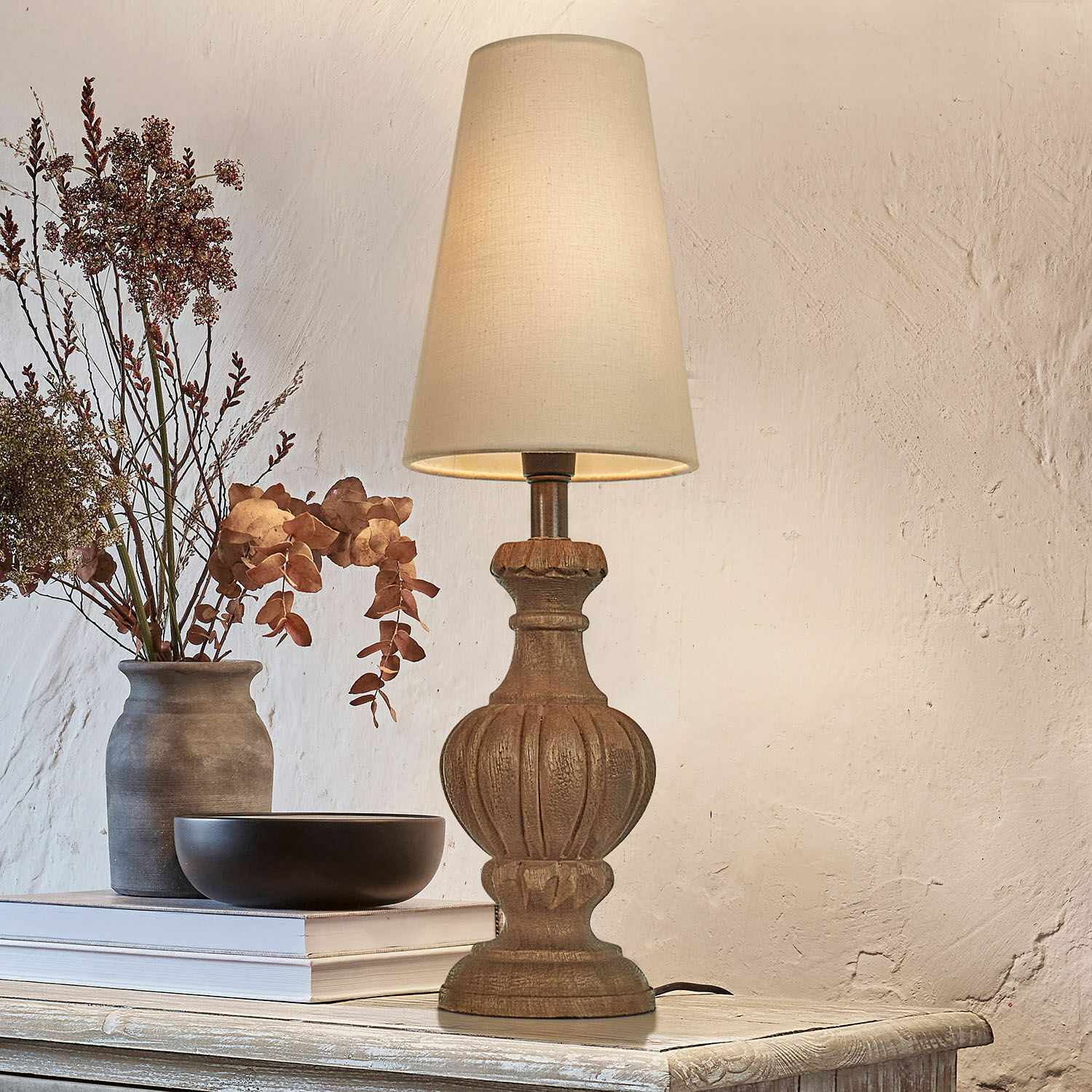 Tischlampe Airoux Tischlampe mit geschnitztem Holzfuss und cremefarbenem Lampenschirm auf rustikalem Tisch