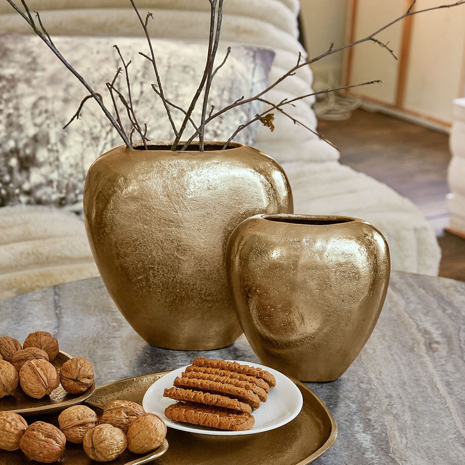 Set mit zwei goldfarbenen Keramikvasen auf Tisch mit Nüssen und Keksen, Wohnaccessoire