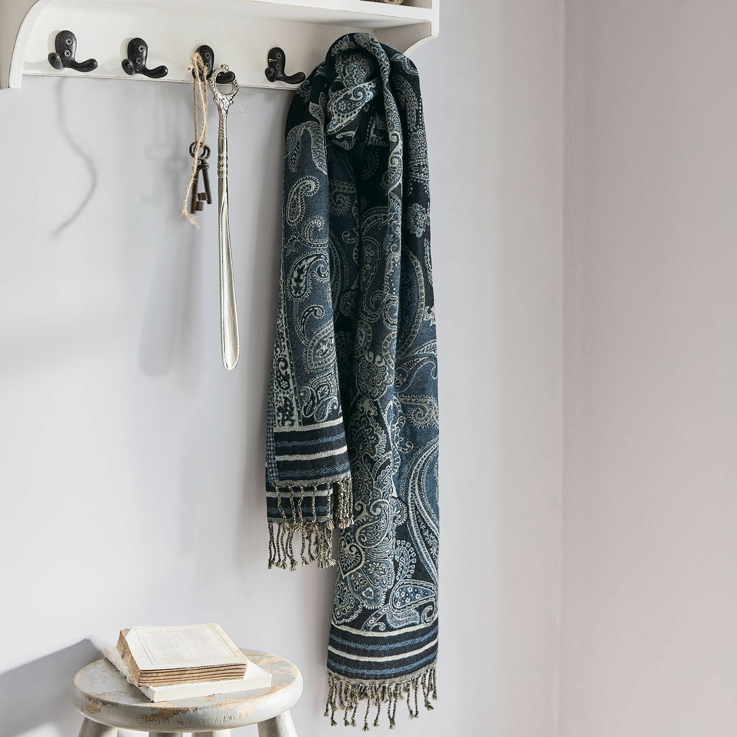Schal Eloas Dunkelblauer Schal mit Paisley-Muster und Fransen an weissem Haken in hellem Raum
