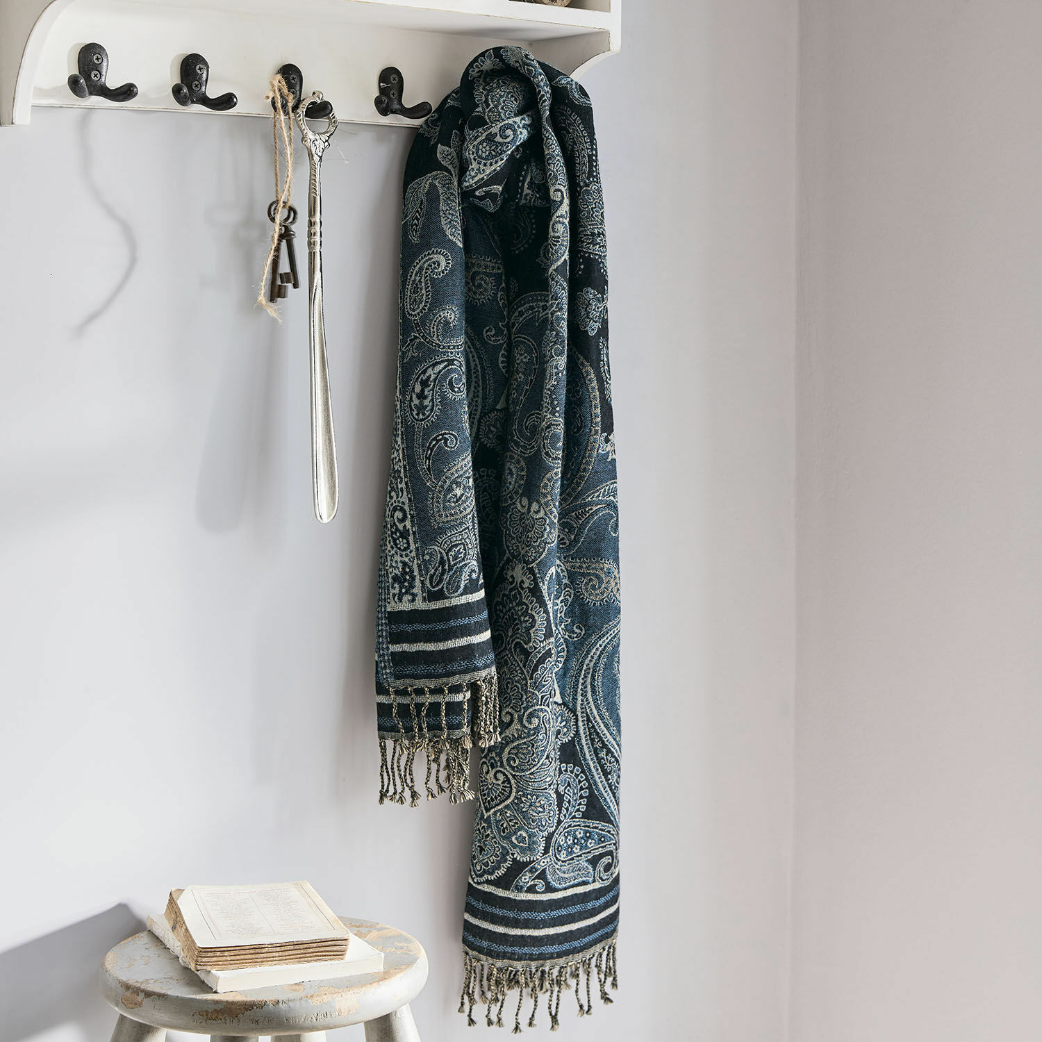 Schal Eloas Dunkelblauer Schal mit Paisley-Muster und Fransen an weissem Haken in hellem Raum