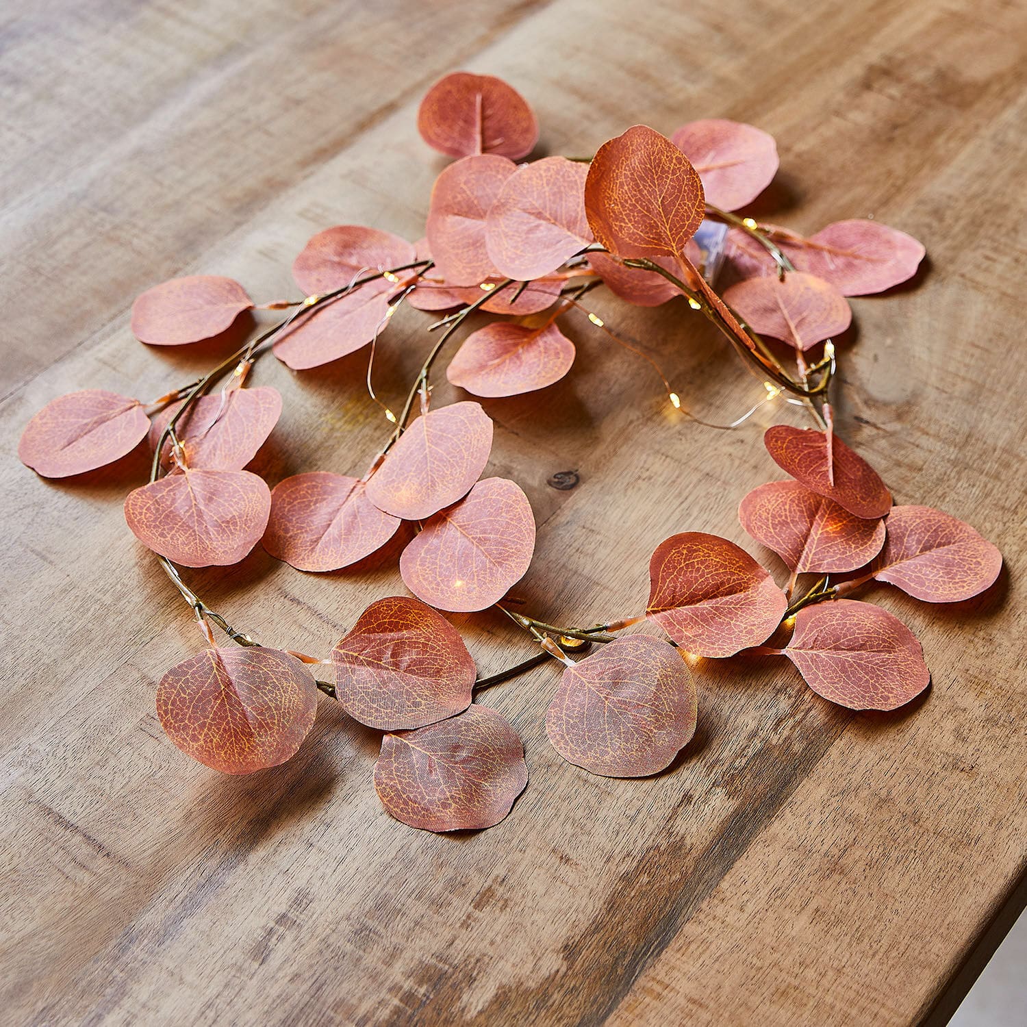 Lichterkette Gracielle Dekorativer Kranz mit rosa Blättern und feiner LED-Beleuchtung auf Holztisch