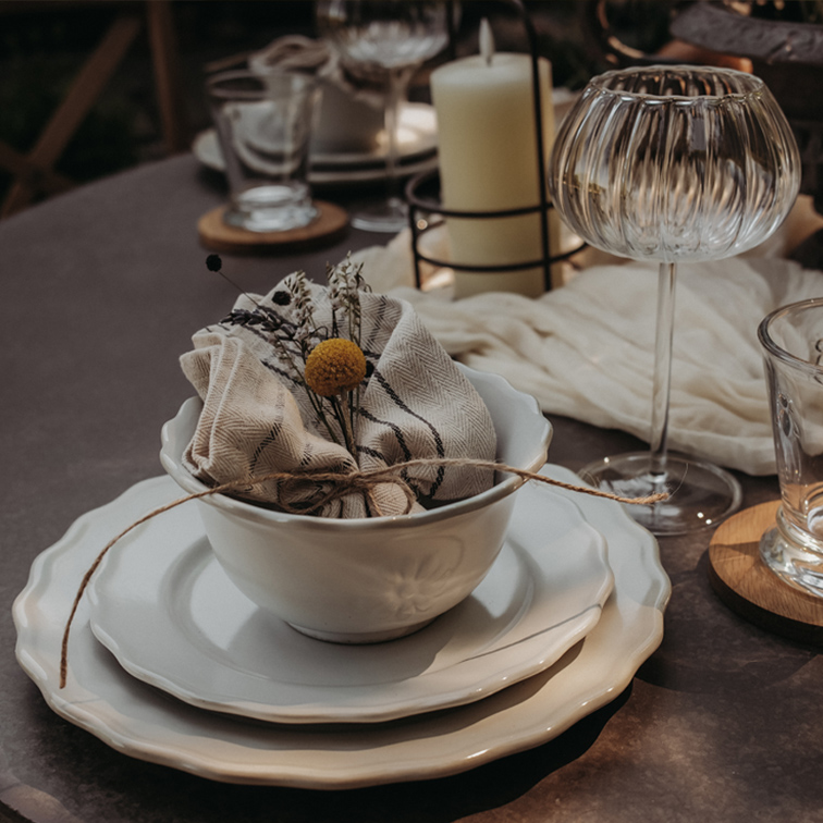 Set aus weisser Keramik mit Schüssel, Tellern und Leinenserviette mit Blumendekor auf Tisch