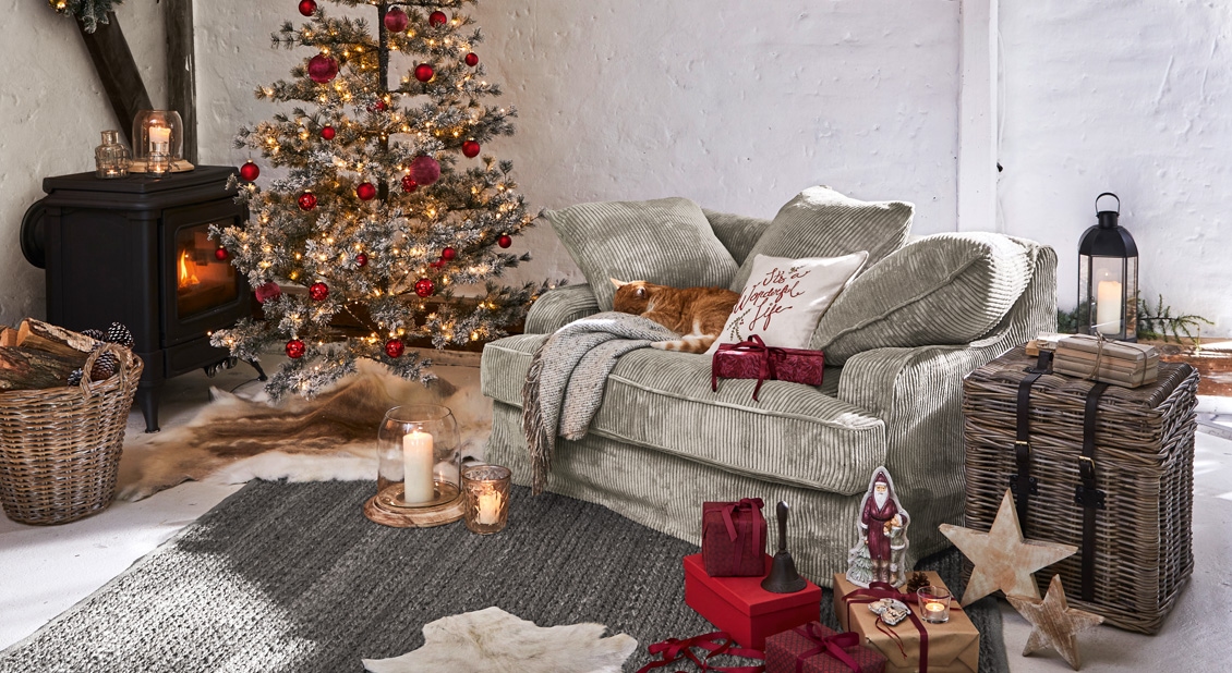 Gemütliches Wohnzimmer mit grünem Sofa, geschmücktem Christbaum und festlicher Dekoration