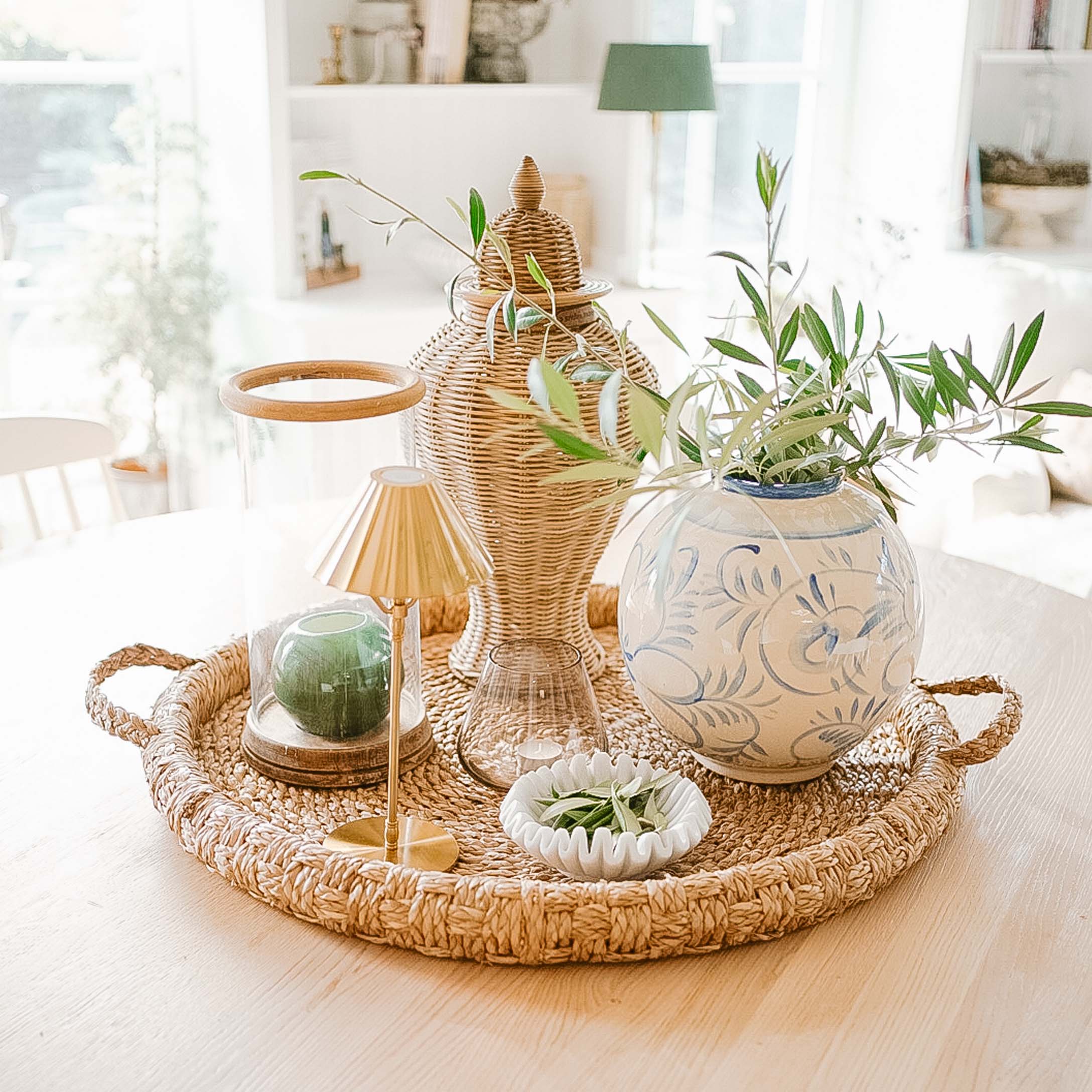 Rattantablett mit Keramikvase und grünen Zweigen als natürliche Wohnraumdekoration