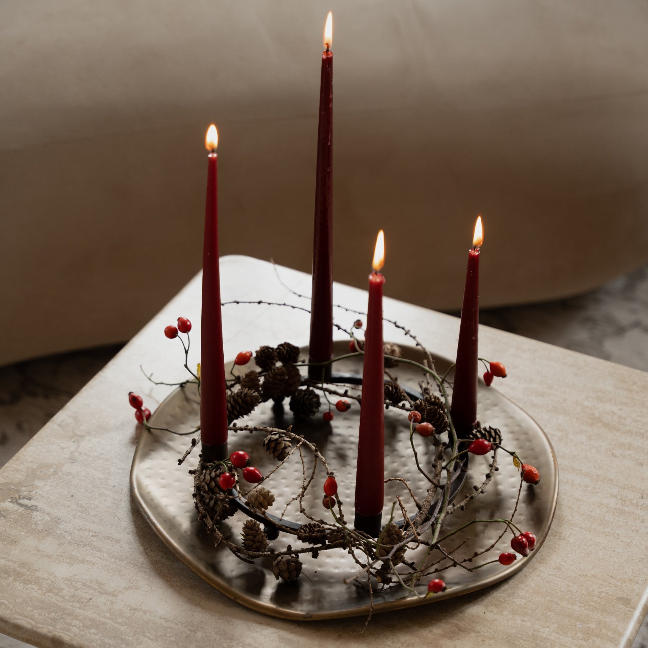 Dekorativer Adventskranz mit roten Kerzen und Zapfen auf einer Metallplatte auf dem Tisch