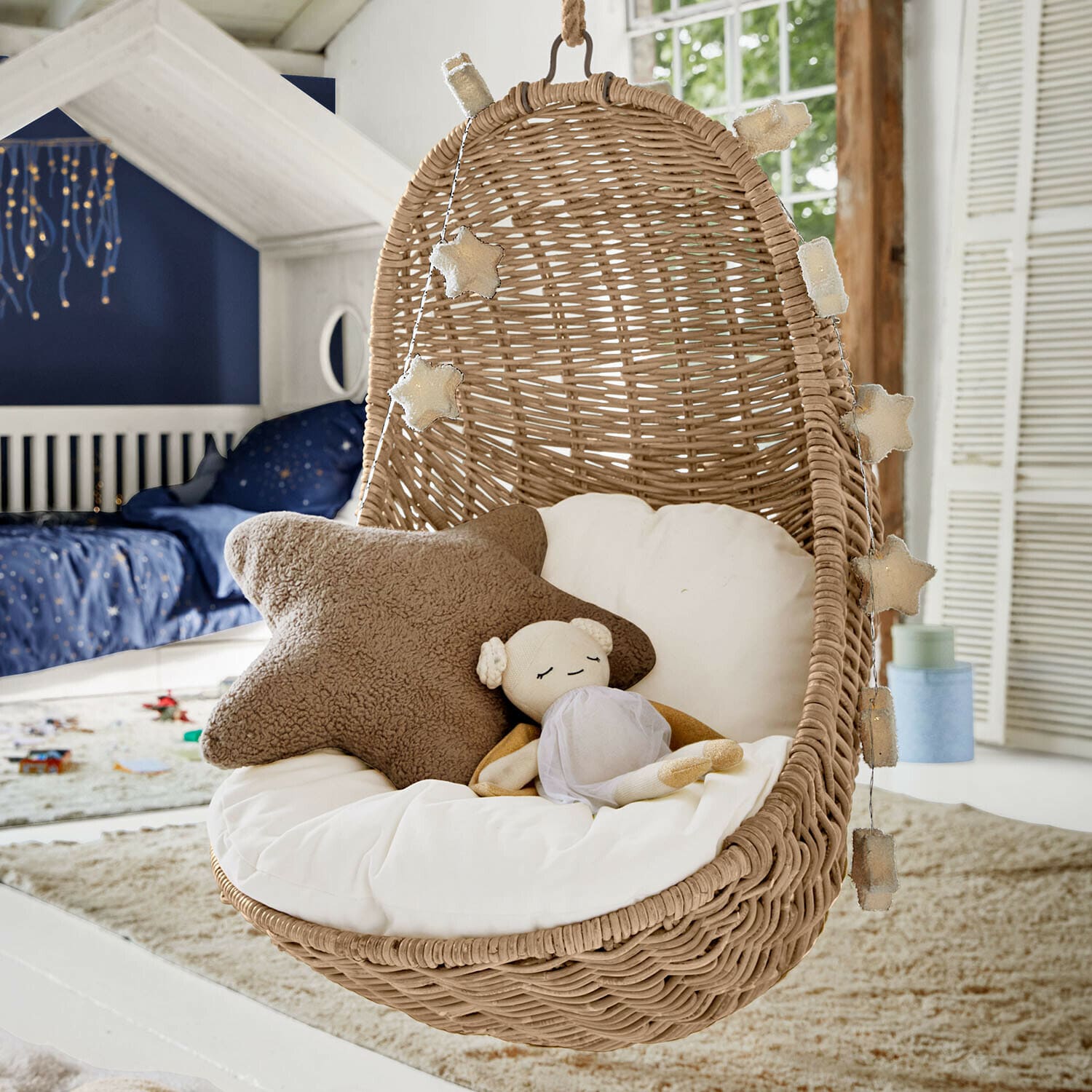 Kinderhängesessel Twinkla Hängesessel aus Rattan mit weissem Kissen und Stern-Lichterkette im Kinderzimmer