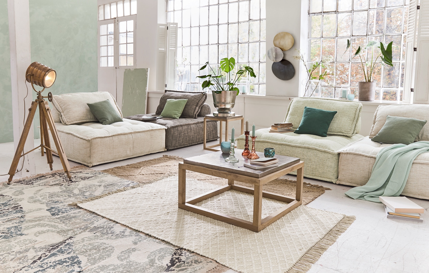 Gemütliches Wohnzimmer mit beigen und grauen Sofas, Holztisch und Loft-Standlampe
