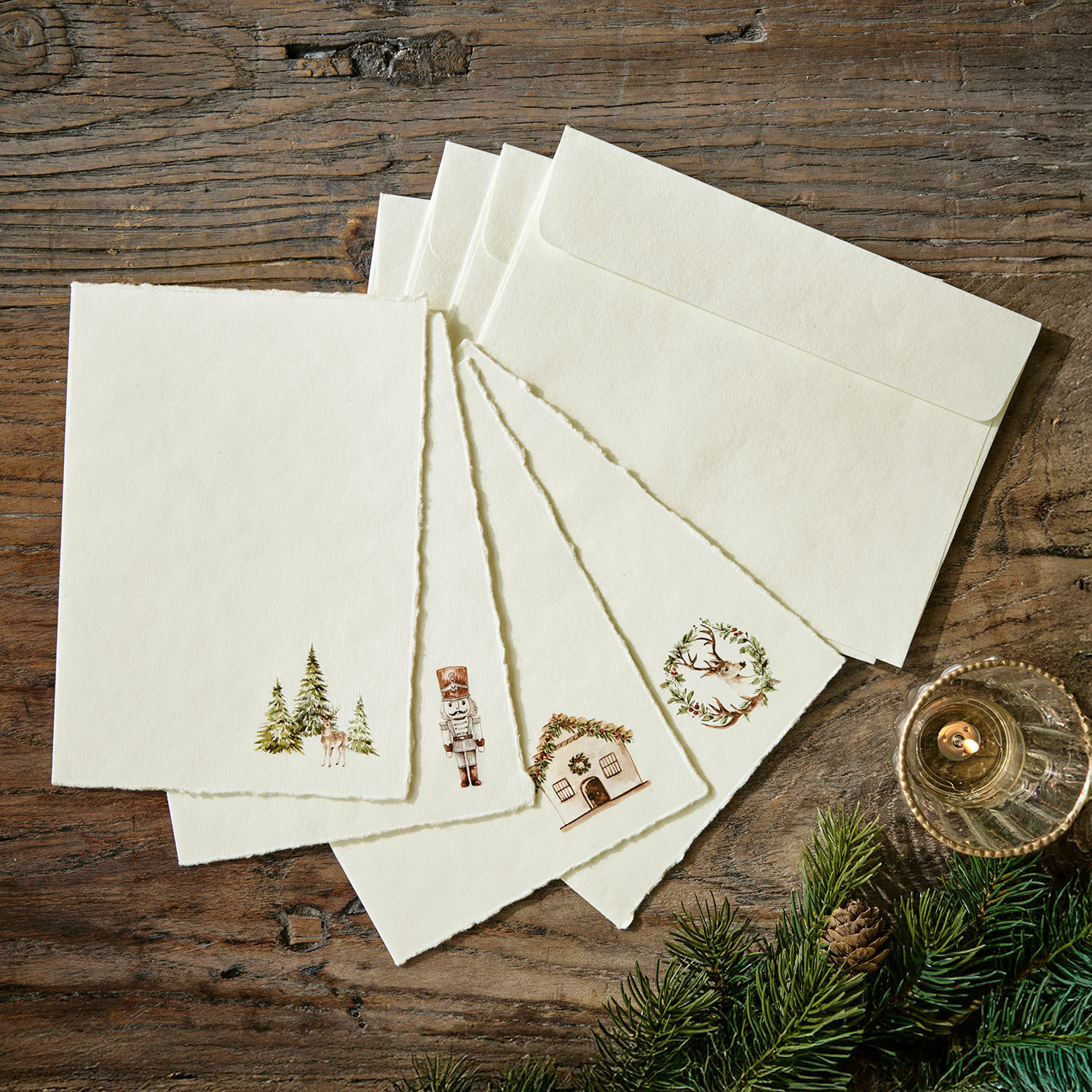 Grusskarte 4er Set Lorandis Set aus cremefarbenen Briefkarten und Umschlägen mit Weihnachtsmotiven auf Holztisch mit Tannenzweigen