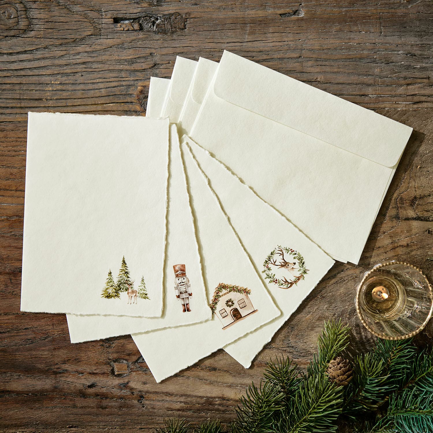 Grusskarte 4er Set Lorandis Set aus cremefarbenen Briefkarten und Umschlägen mit Weihnachtsmotiven auf Holztisch mit Tannenzweigen