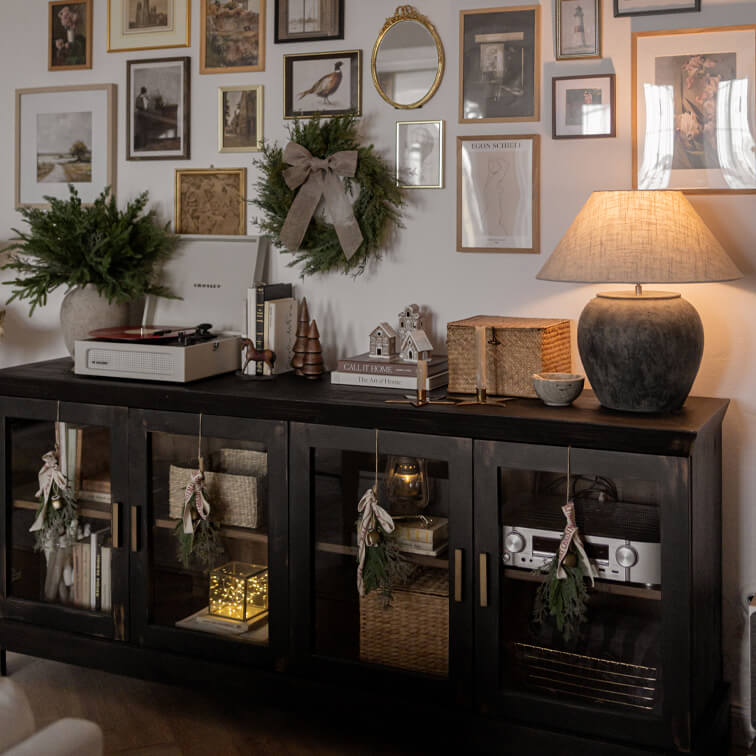 Schwarzes Holzsideboard mit Glastüren, weihnachtlicher Dekoration und Keramiklampe im Wohnzimmer