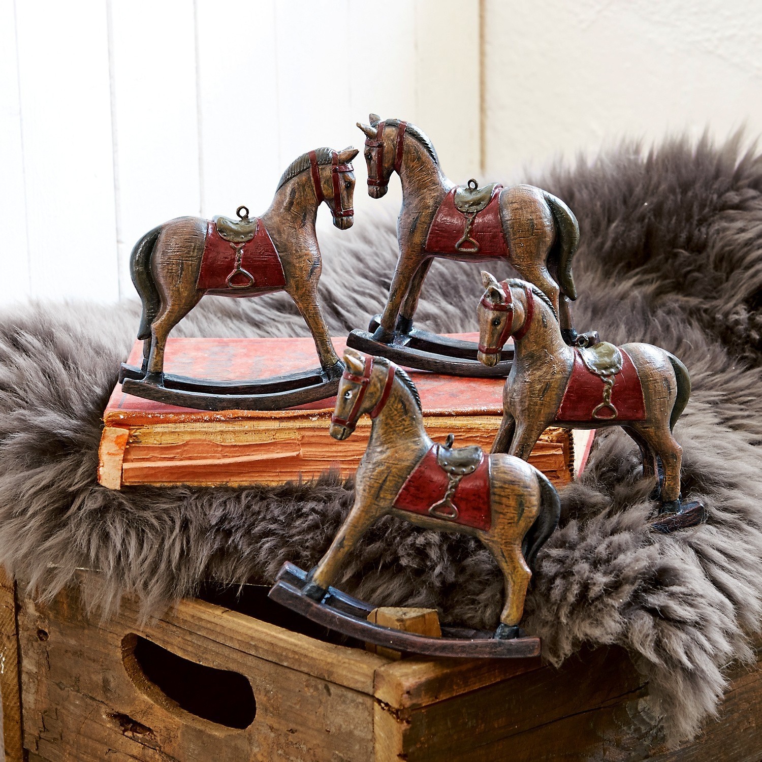 Deko-Pferde 4er Set Cory Vier braune Holzschaukelpferde mit roten Sätteln als rustikale Wohnaccessoires.