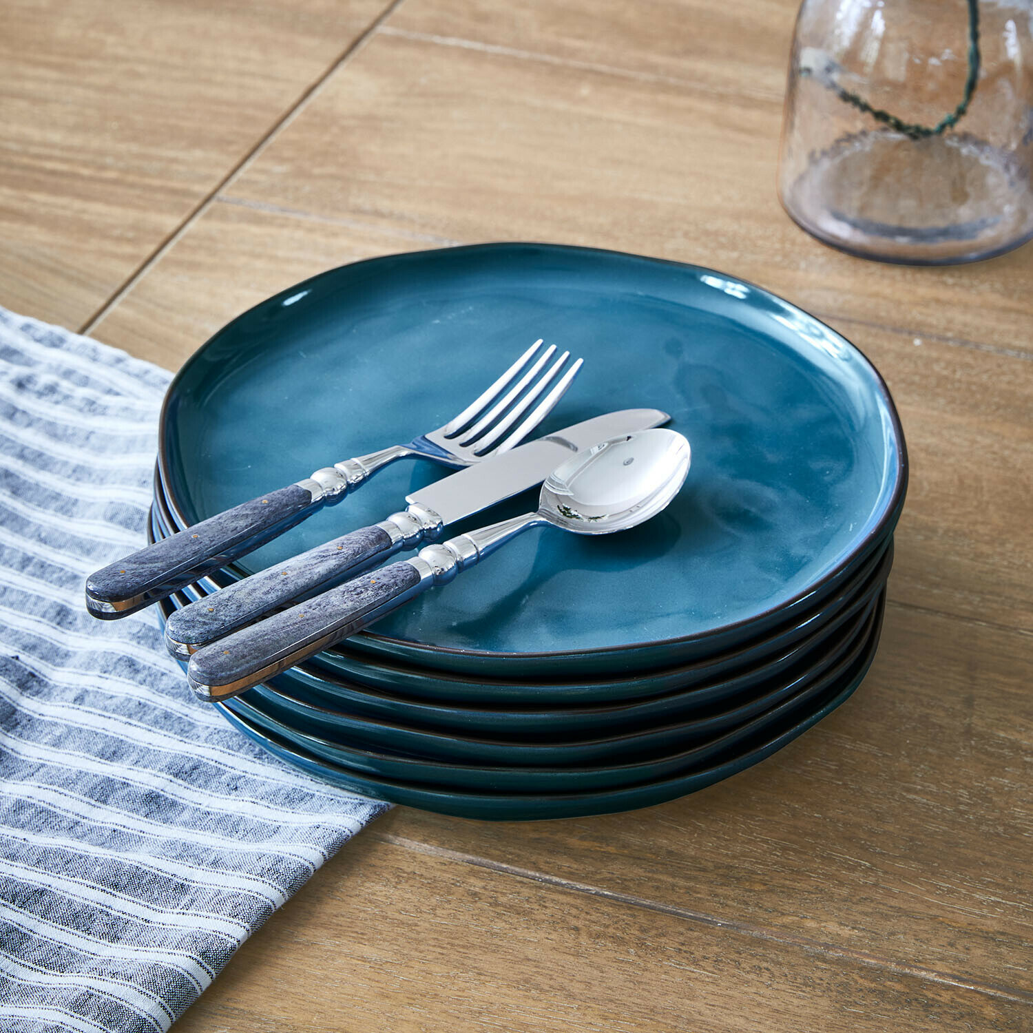 Teller 6er Set Biarré Set aus blauen Keramiktellern mit Metallbesteck und Holzgriffen auf Holztisch