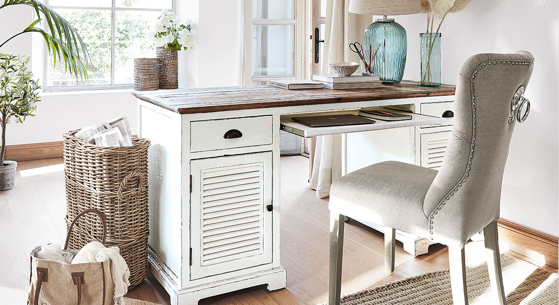 Weisser Holzschreibtisch im Shabby-Chic-Stil mit Schubladen und grauem Polsterstuhl in hellem Raum