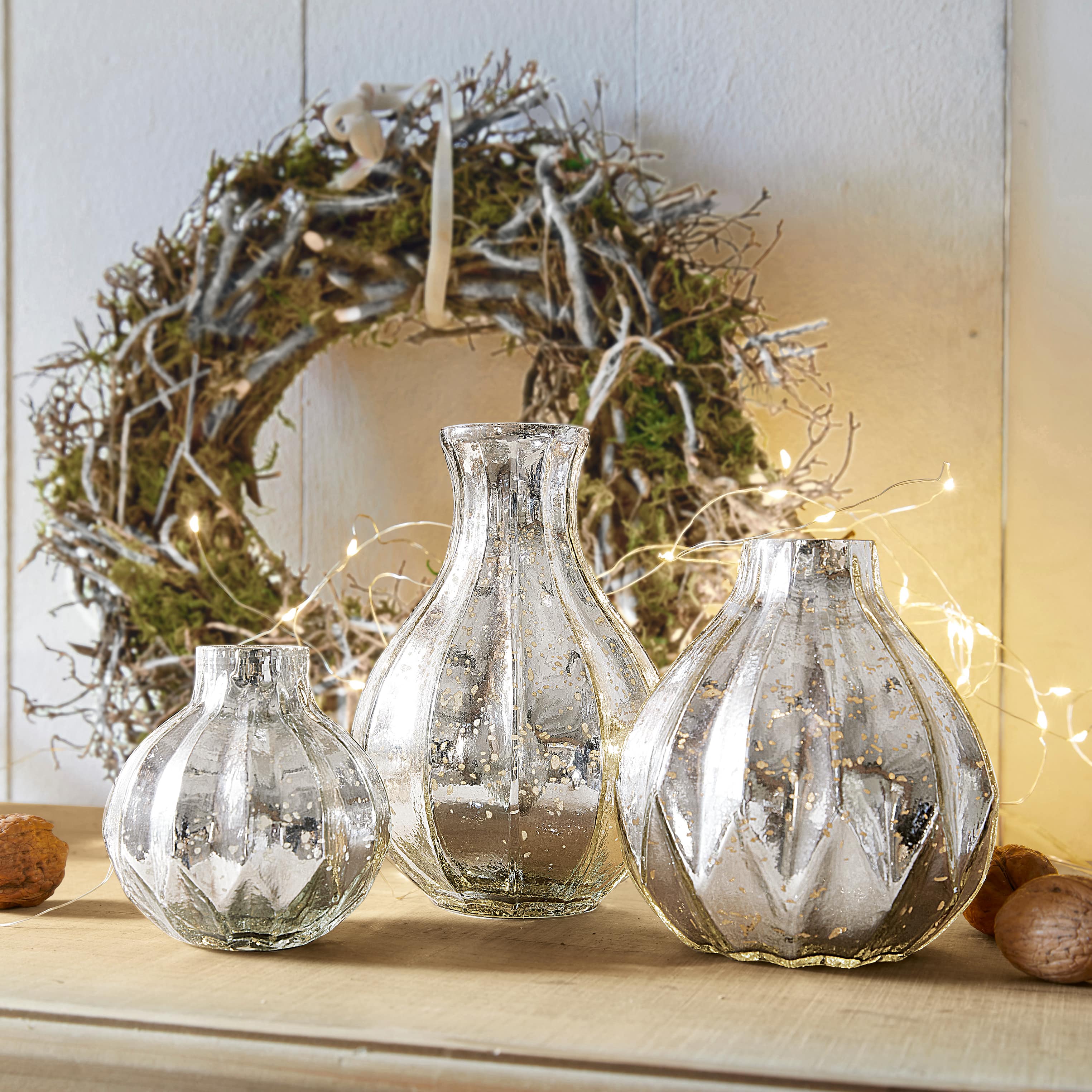 Set mit drei dekorativen Vasen aus silbernem Glas mit antikem Finish auf Holztisch