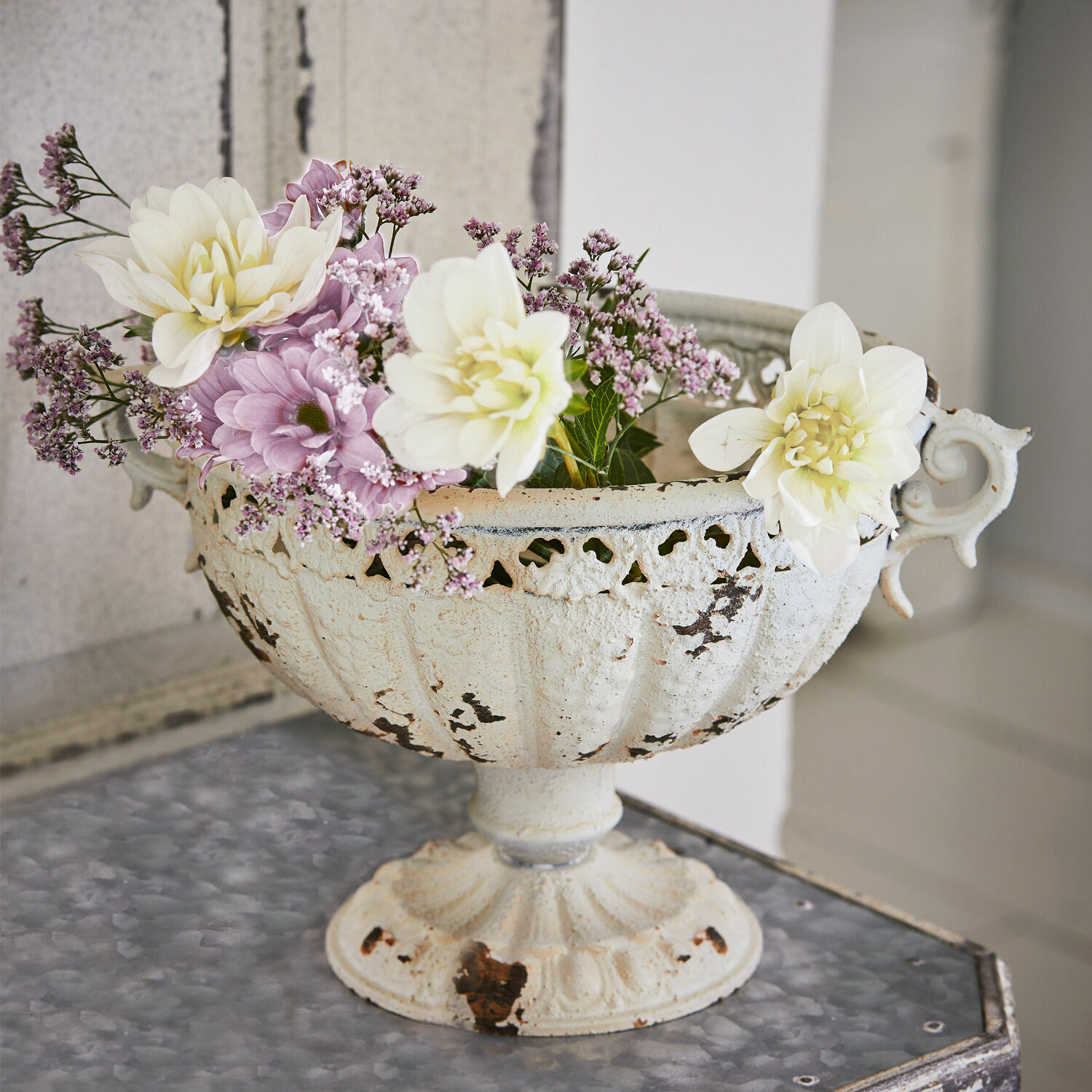 Amphore Vescemont Weisse Metallschale mit antikem Look und pastellfarbenen Blumen auf dekorativem Tisch