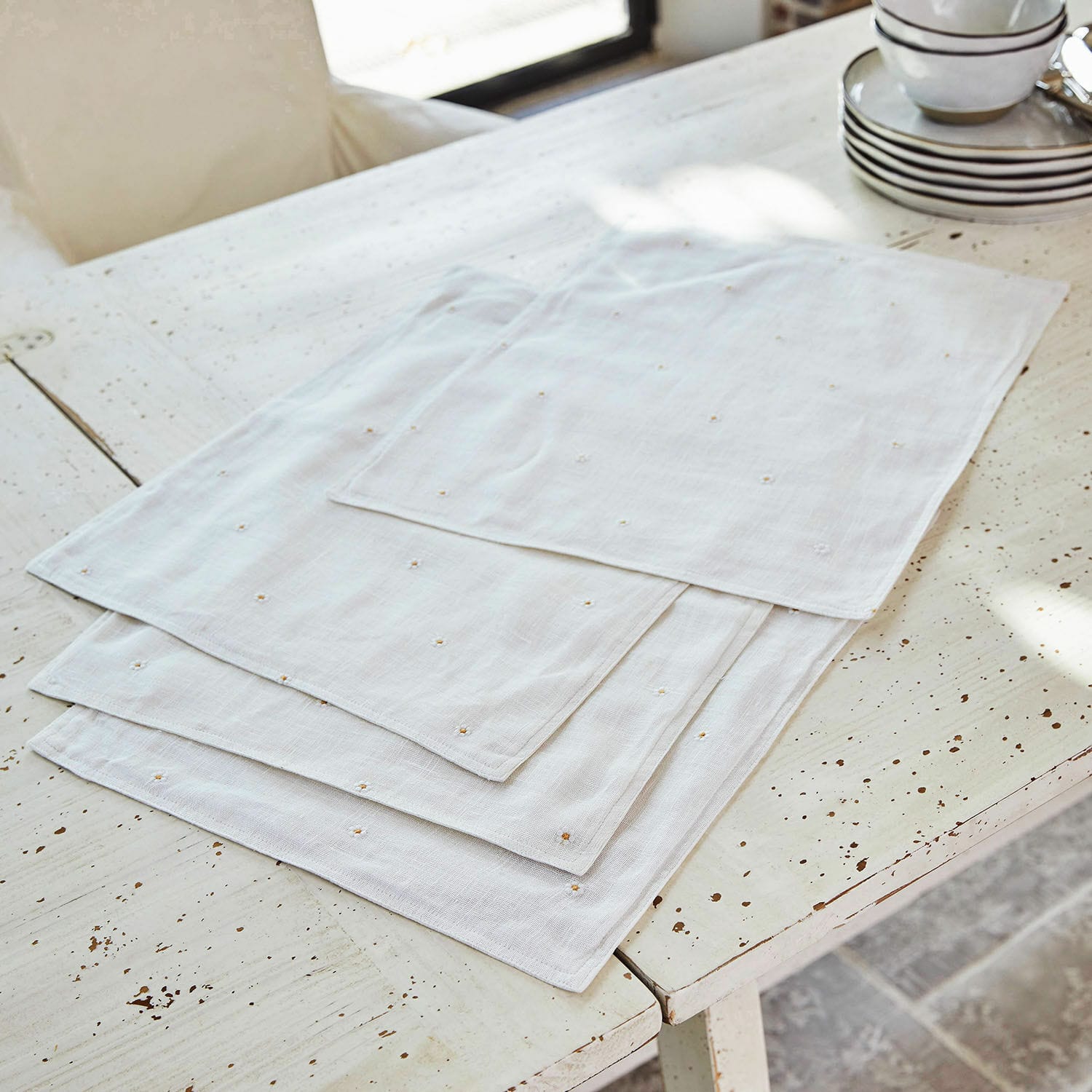Platzset 4er Set Lentilly Weisse Leinenservietten mit feiner Stickerei auf rustikalem Tisch, elegante Tischdekoration