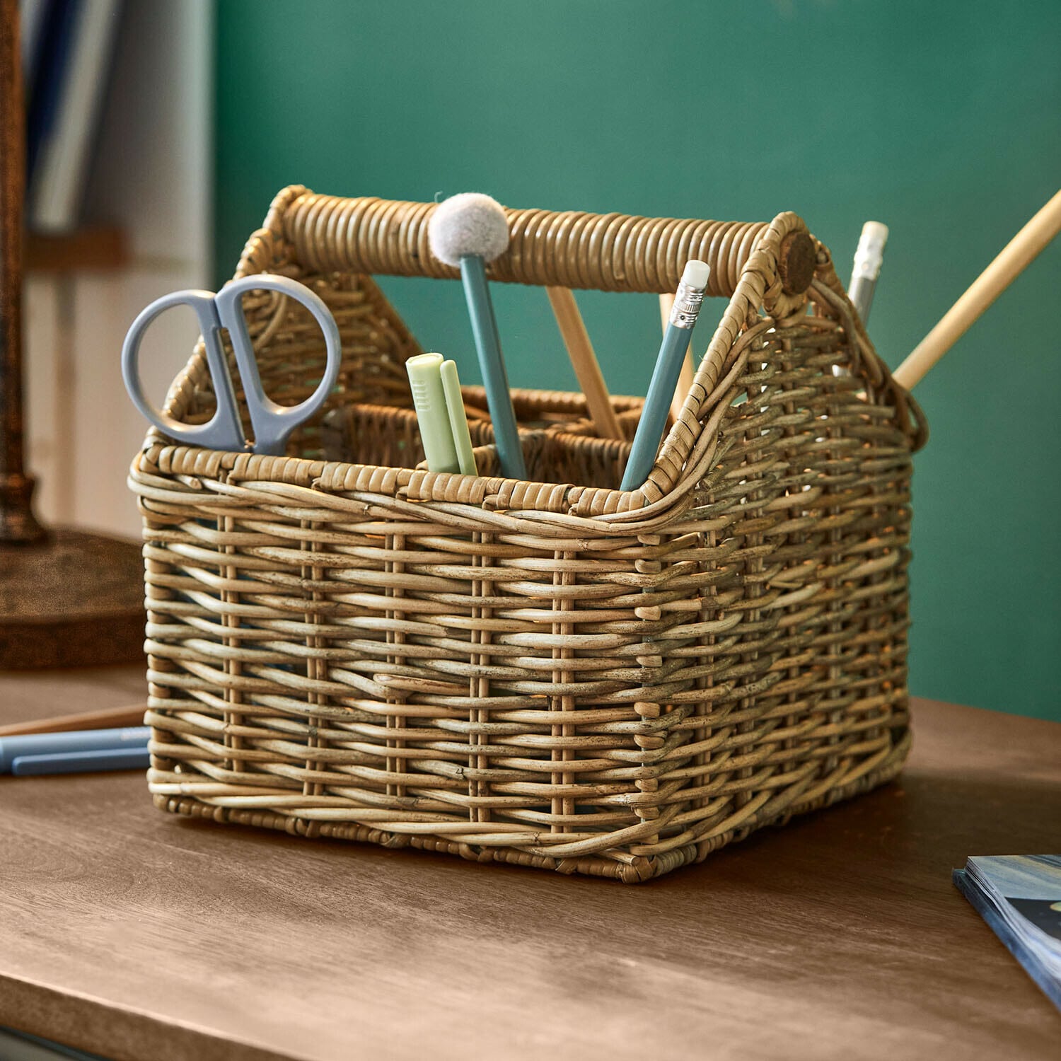 Natürlicher Rattankorb mit Fächern für Schere und Schreibutensilien auf Holztisch