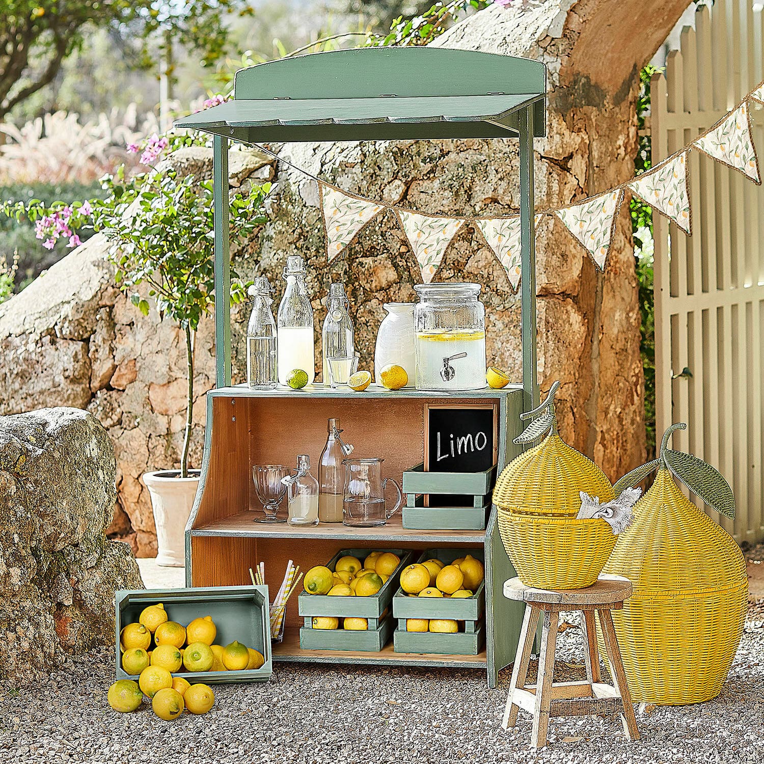 Limonadenstand Éclairon Grüner Holzstand mit Zitronen und Glasflaschen für Limonade im Garten