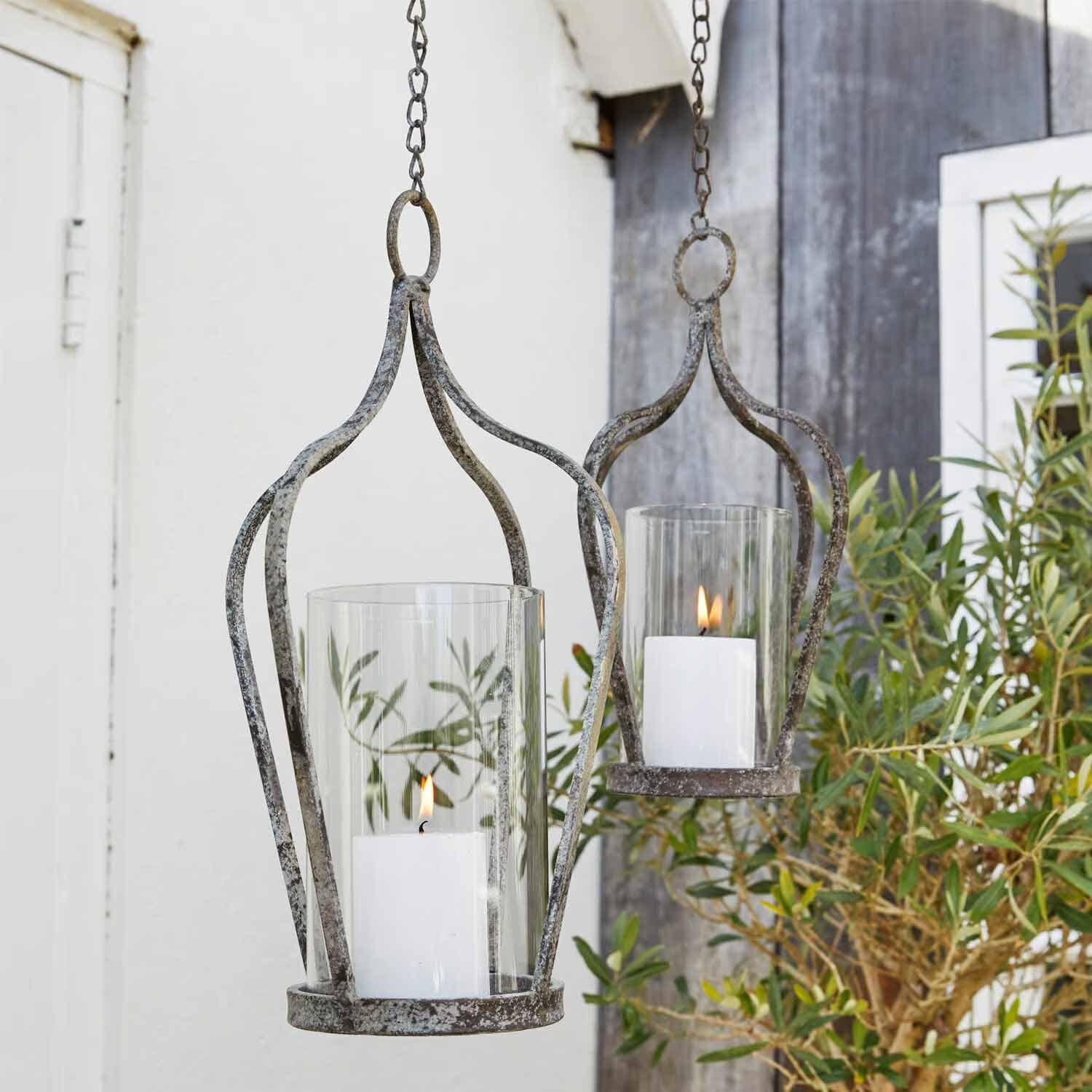 Hängende Metalllaternen im Vintage-Stil mit weissen Kerzen und Glasschutz für Gartendekoration
