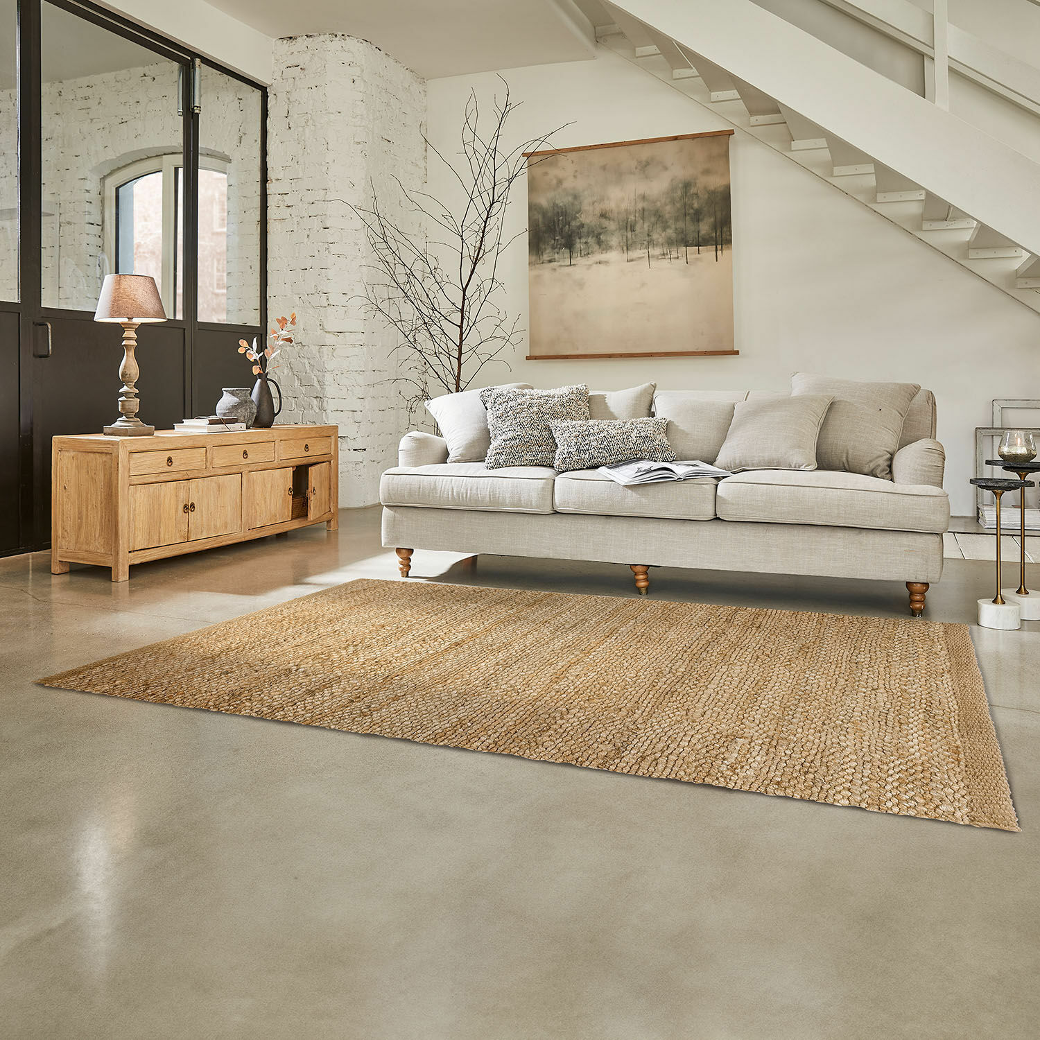 Natürlicher Jute-Teppich in Beige im Wohnzimmer mit hellgrauem Sofa und Holzkommode