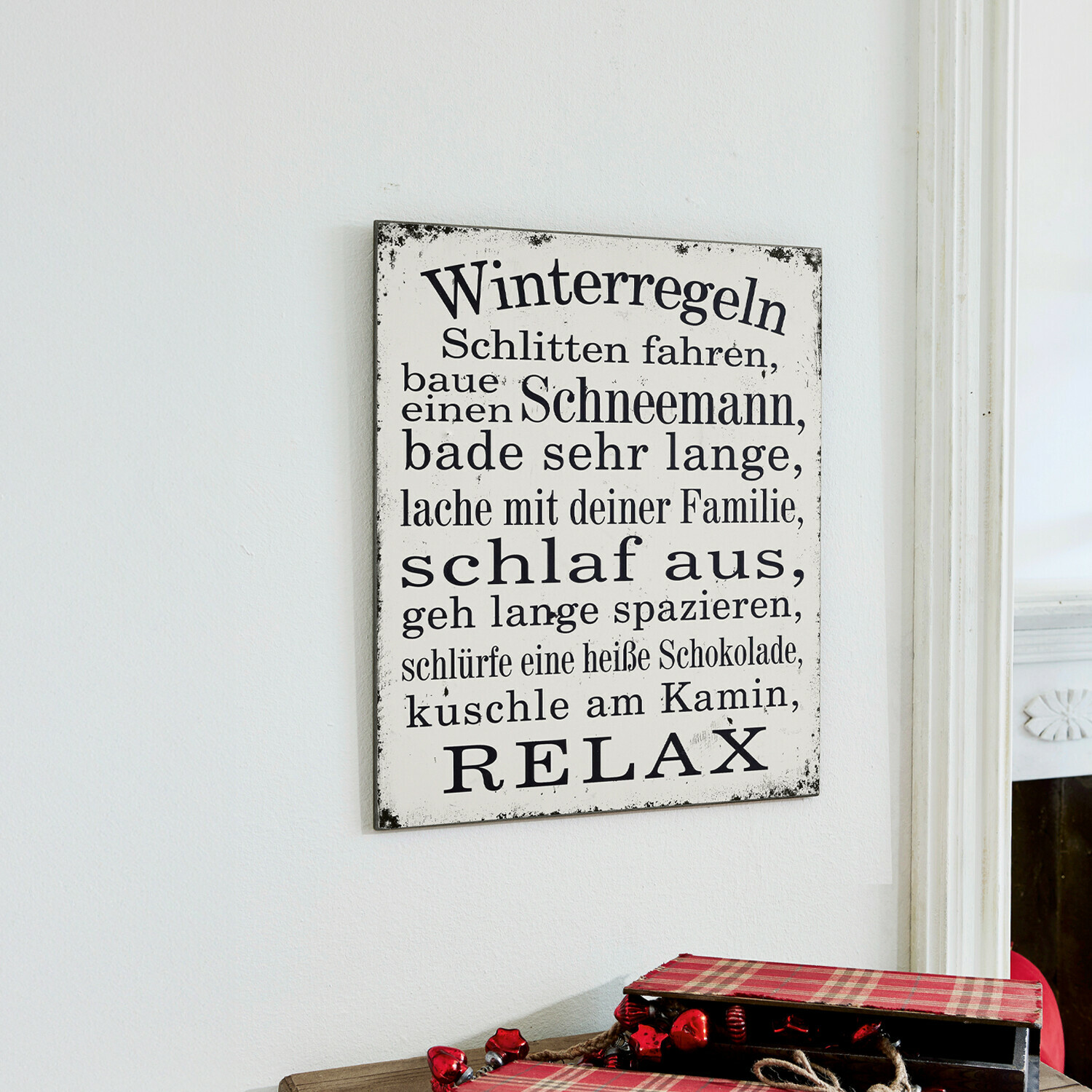 Dekoboard Winterregeln Weisses Metallschild mit schwarzem Winterregeln-Text und brennenden roten Kerzen im Kerzenhalter