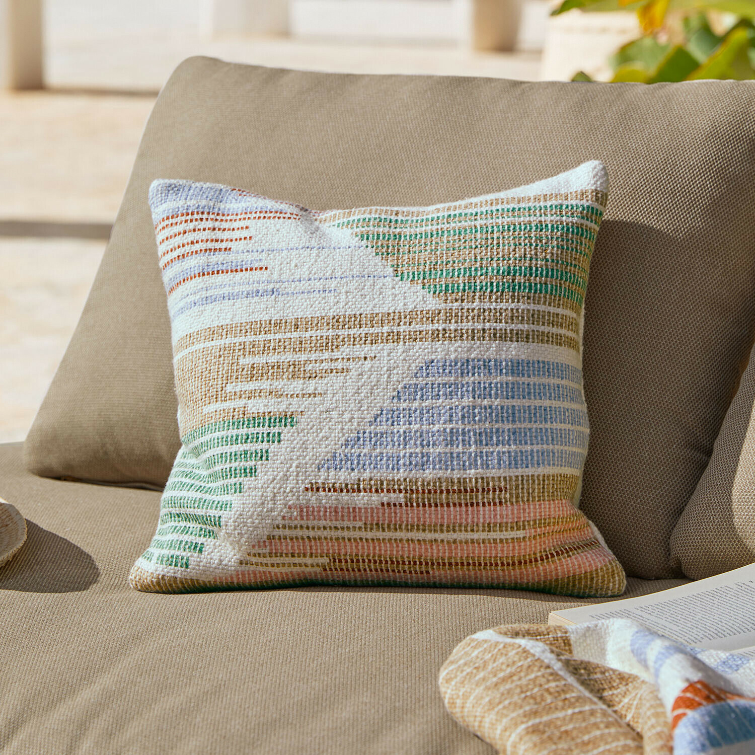 Buntes Baumwoll-Zierkissen mit geometrischem Muster auf beigem Sofa fürs Wohnzimmer