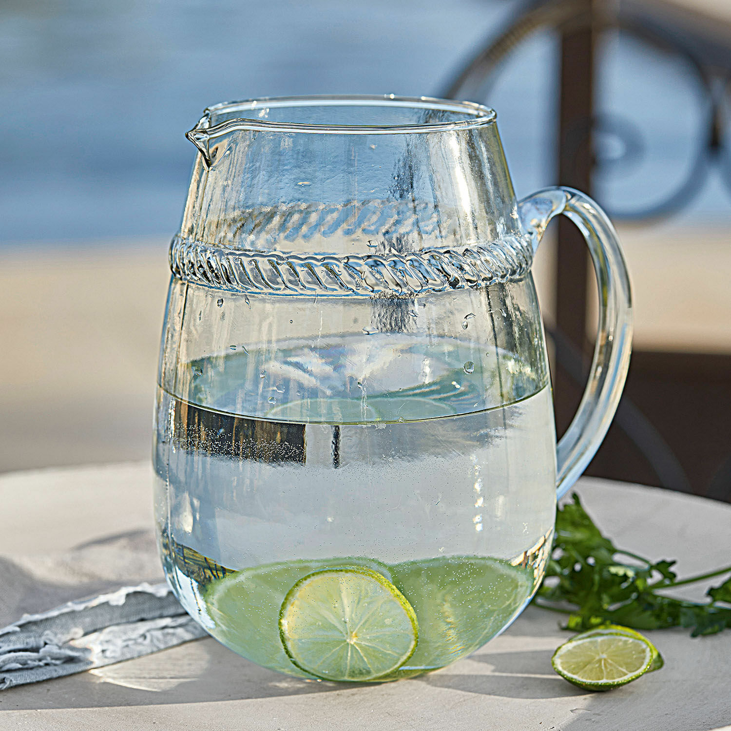 Krug Beiras Glaskrug aus klarem Glas mit Wasser und Limettenscheiben auf dem Gartentisch