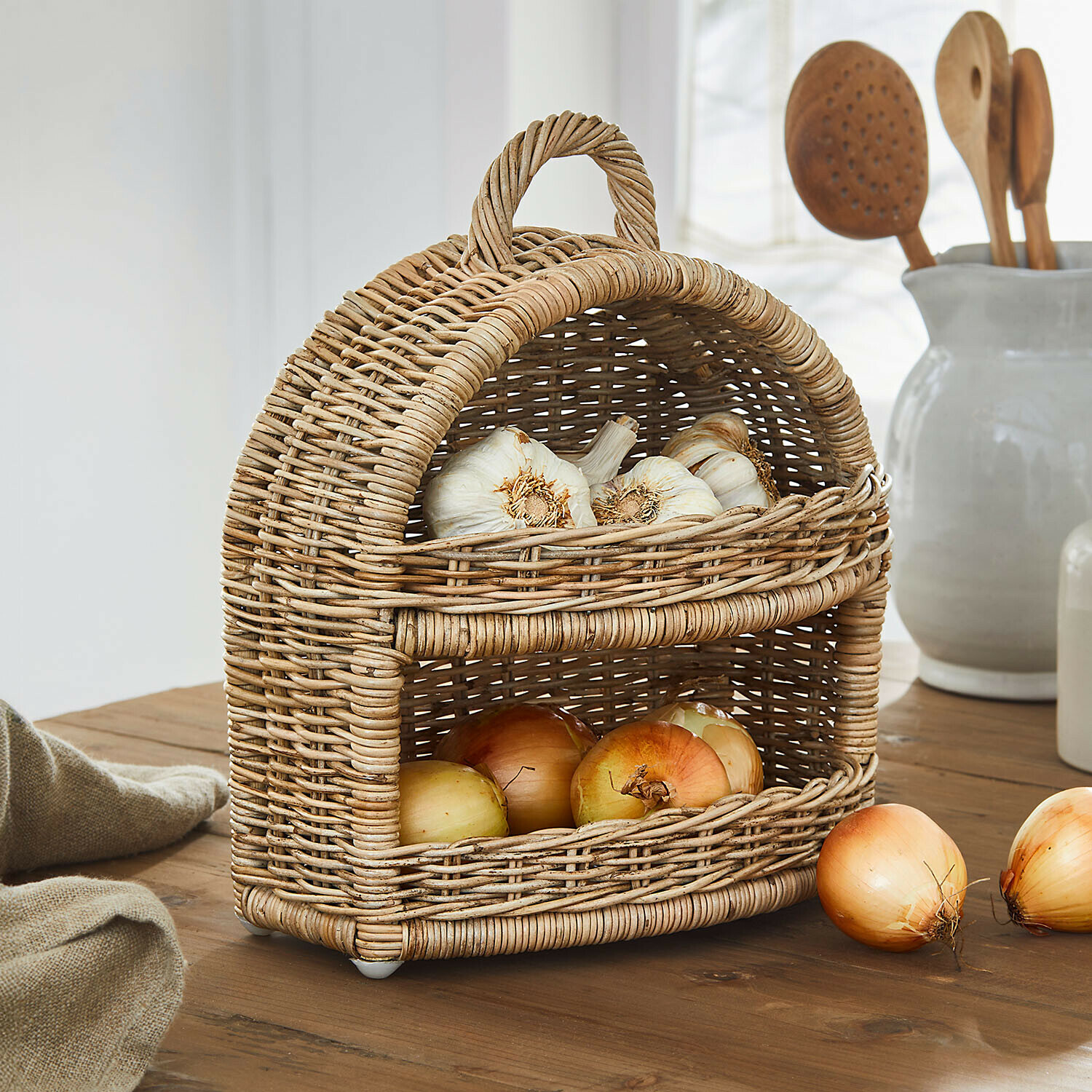 Zwiebelkorb Coudrisse Zweistöckiger Korb aus natürlichem Rattan mit Knoblauch und Zwiebeln auf rustikalem Holztisch