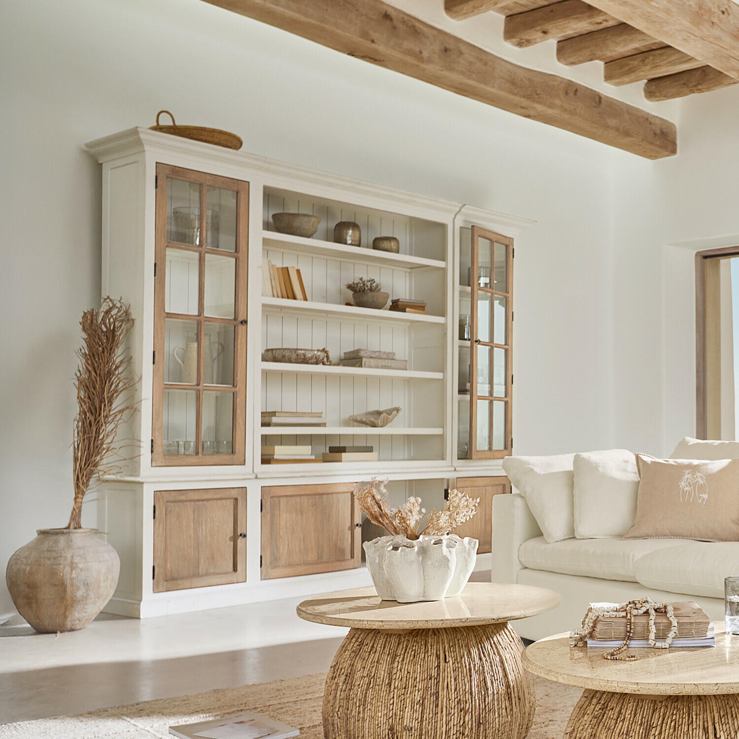 Heller Holzschrank mit Glastüren und natürlichen Dekorationen in einem hellen Wohnzimmer
