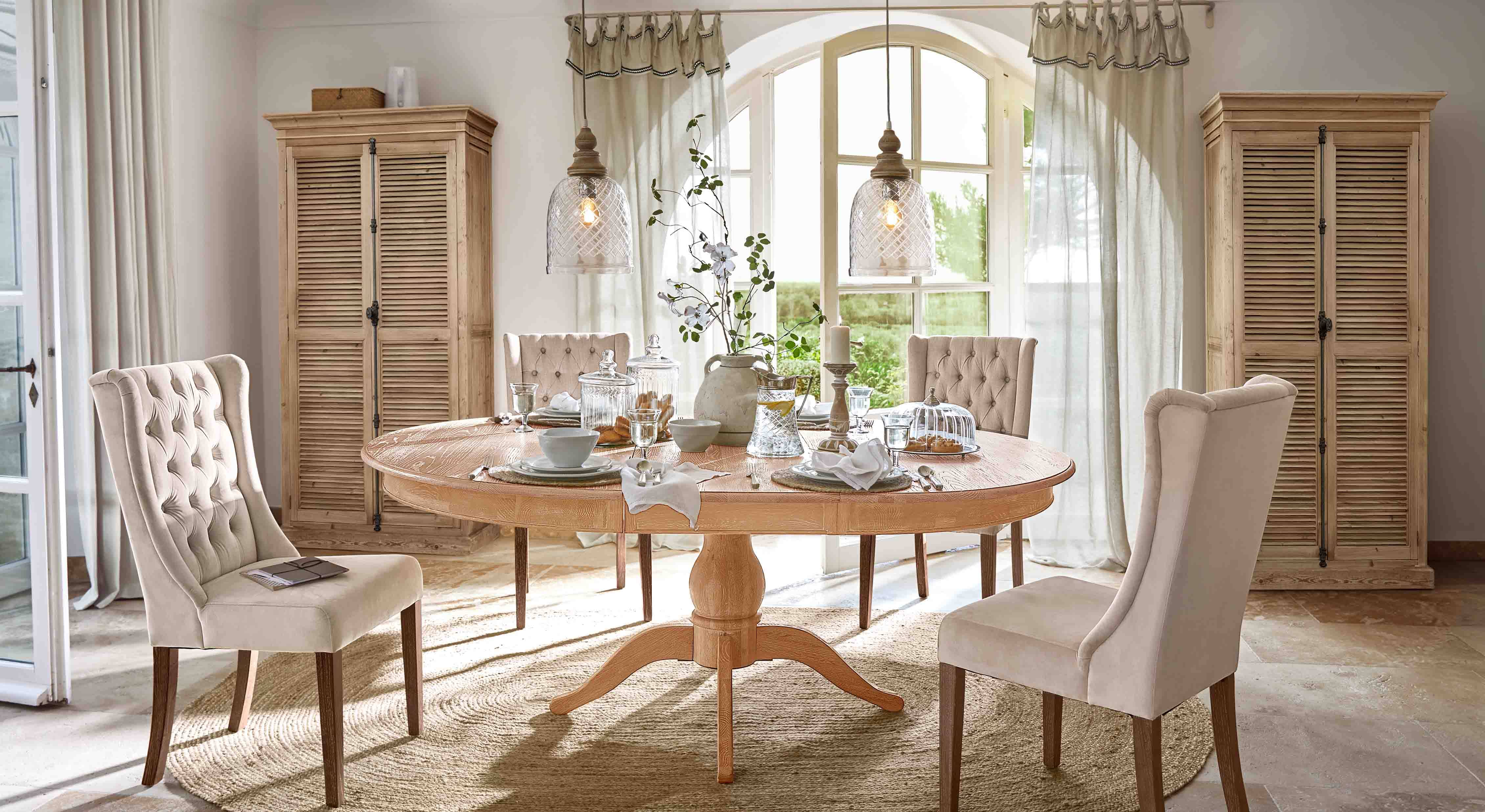 Esszimmer mit rundem Holztisch und beige gepolsterten Stühlen im klassischen Landhausstil
