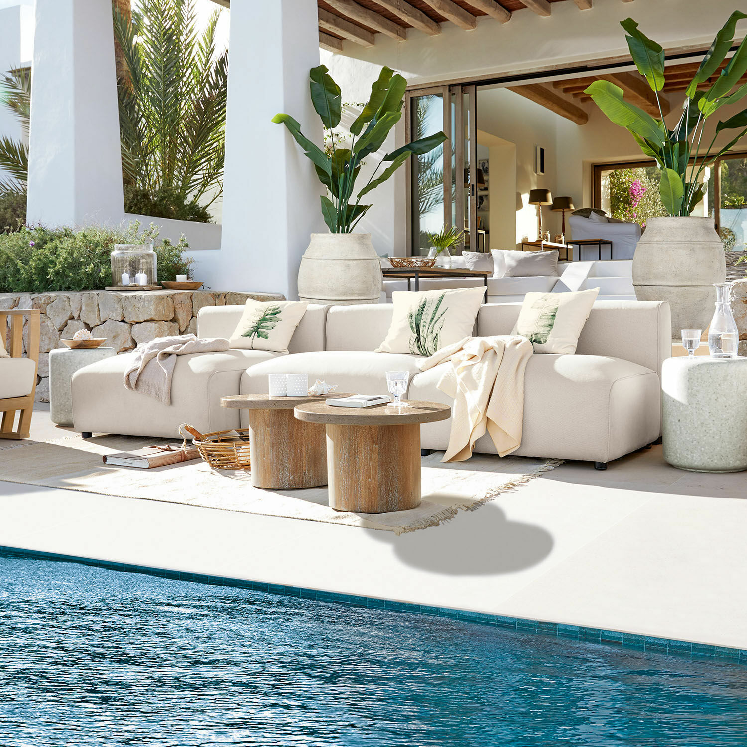 Sitzgruppe Vézère Beiges Stoffsofa auf der Terrasse am Pool mit Holztischen und dekorativen Kissen in natürlicher Umgebung