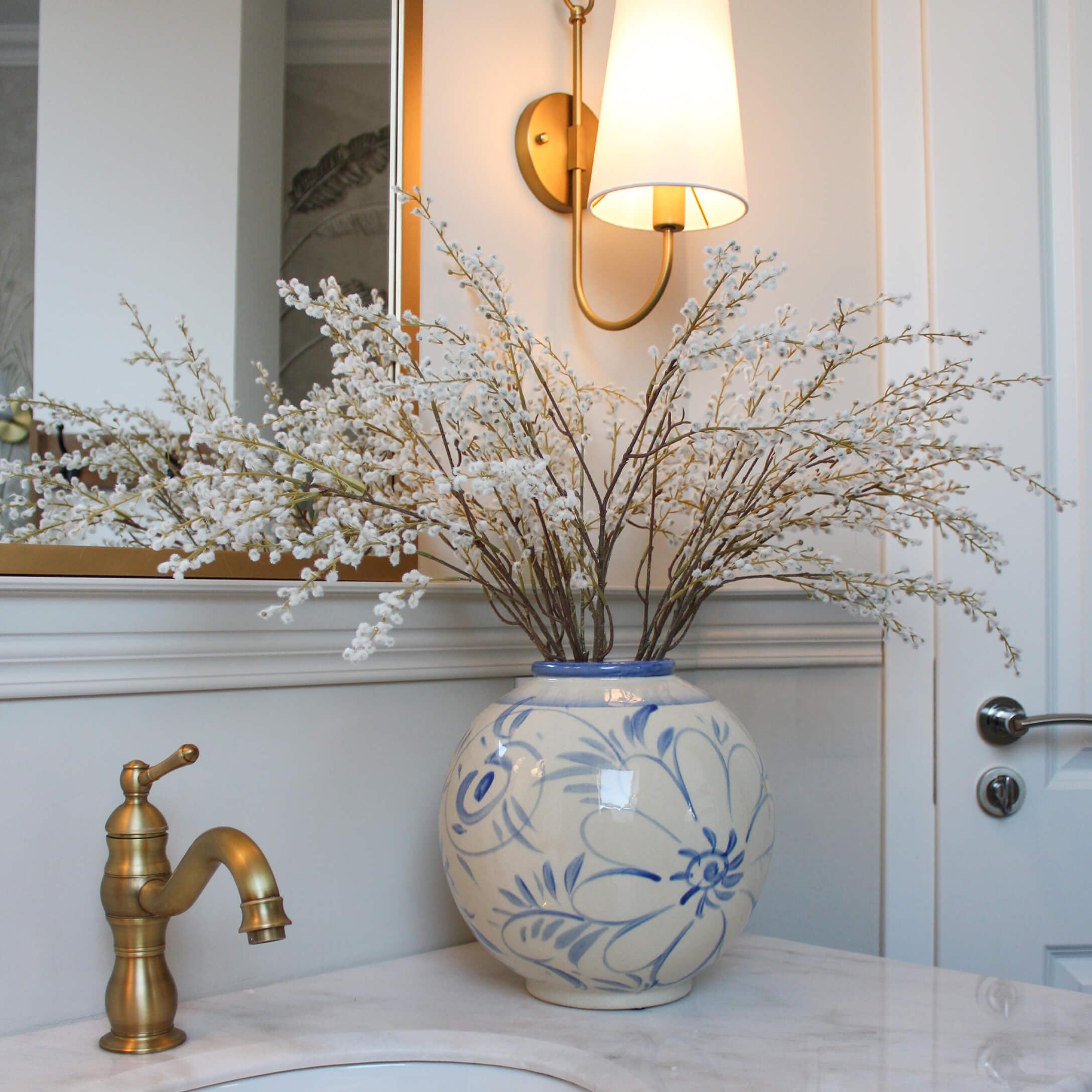 Keramikvase mit blauem Blumenmuster und weissen Blütenzweigen auf Marmor-Waschbeckenablage im Badezimmer