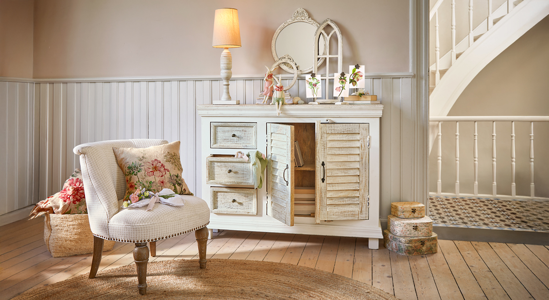 Weisse Holzkommode mit Used-Look und floralen Dekorationen im gemütlichen Cottage-Stil