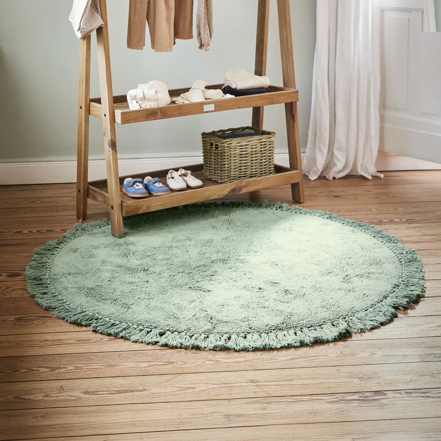 Runder weicher Teppich in Grün mit Fransen auf Holzboden im Kinderzimmer