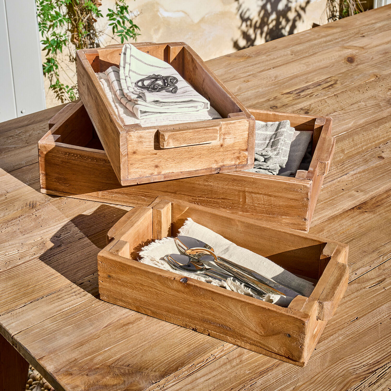 Box 3er Set Tarevo Drei natürliche Holztabletts mit Griffen auf Holztisch, mit Servietten und Besteck dekoriert