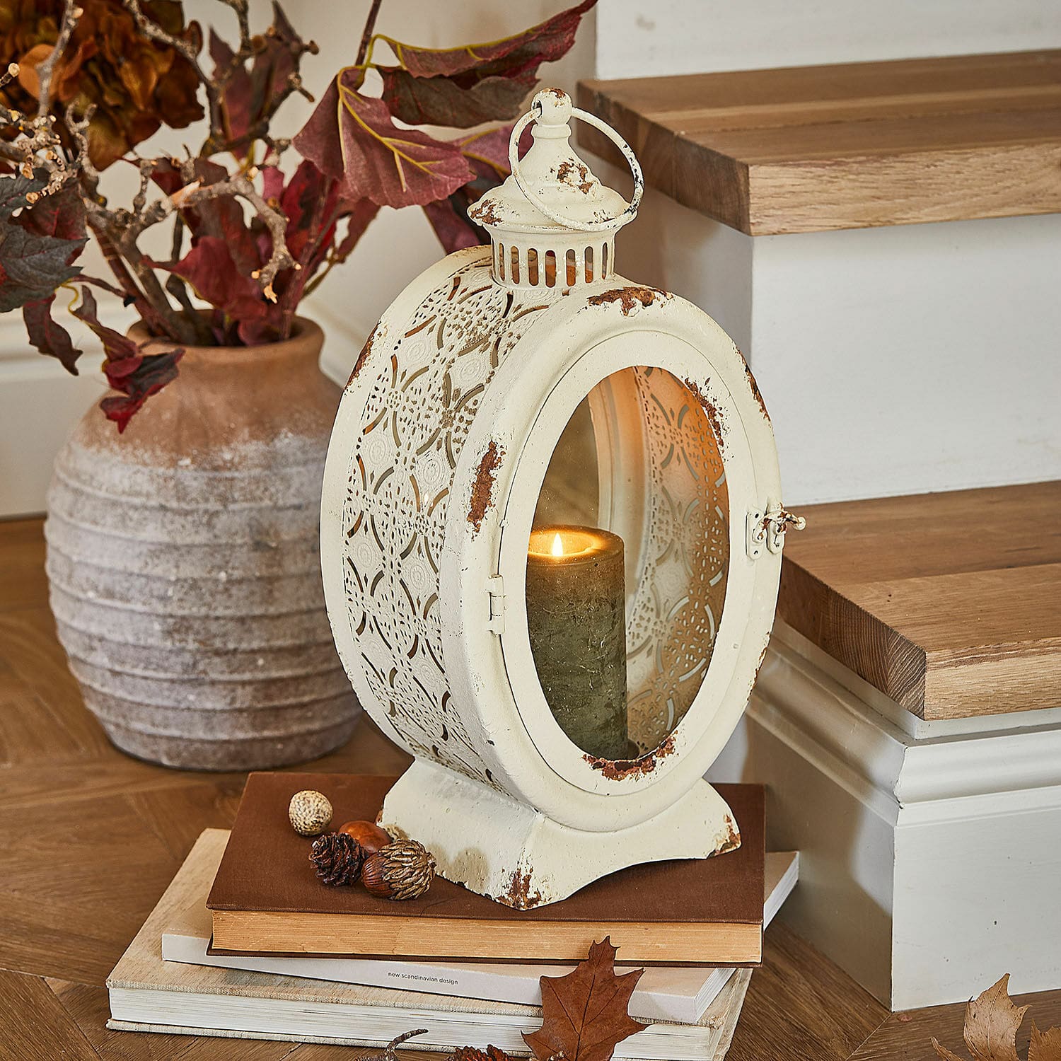Laterne Sublimelle Vintage-Metalllaterne in Creme mit brennender Kerze und herbstlicher Dekoration auf Büchern