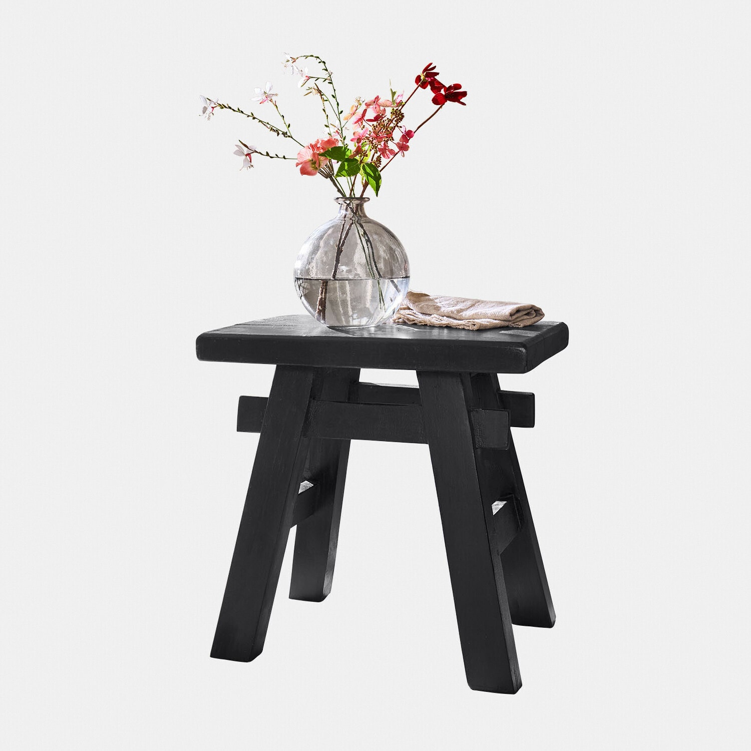 Hocker Oaklynne Schwarzer Holzschemel mit rundem transparentem Glasvase und Blumen darauf